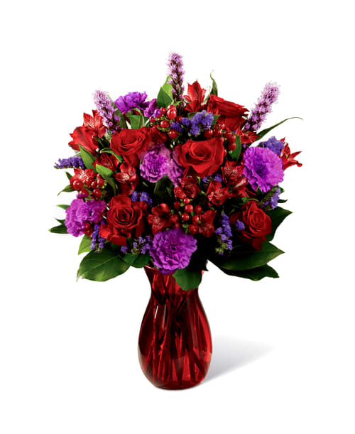 Ravishing Red  - Love makes the world go round and this fresh flower arrangement is out to prove it with it's deep, romantic coloring and, oh, so sophisticated styling. Rich red roses mingle with red Peruvian Lilies, purple carnations, purple statice, red hypericum berries, liatris, and fresh greens.  Vases may vary depending on stock availability.