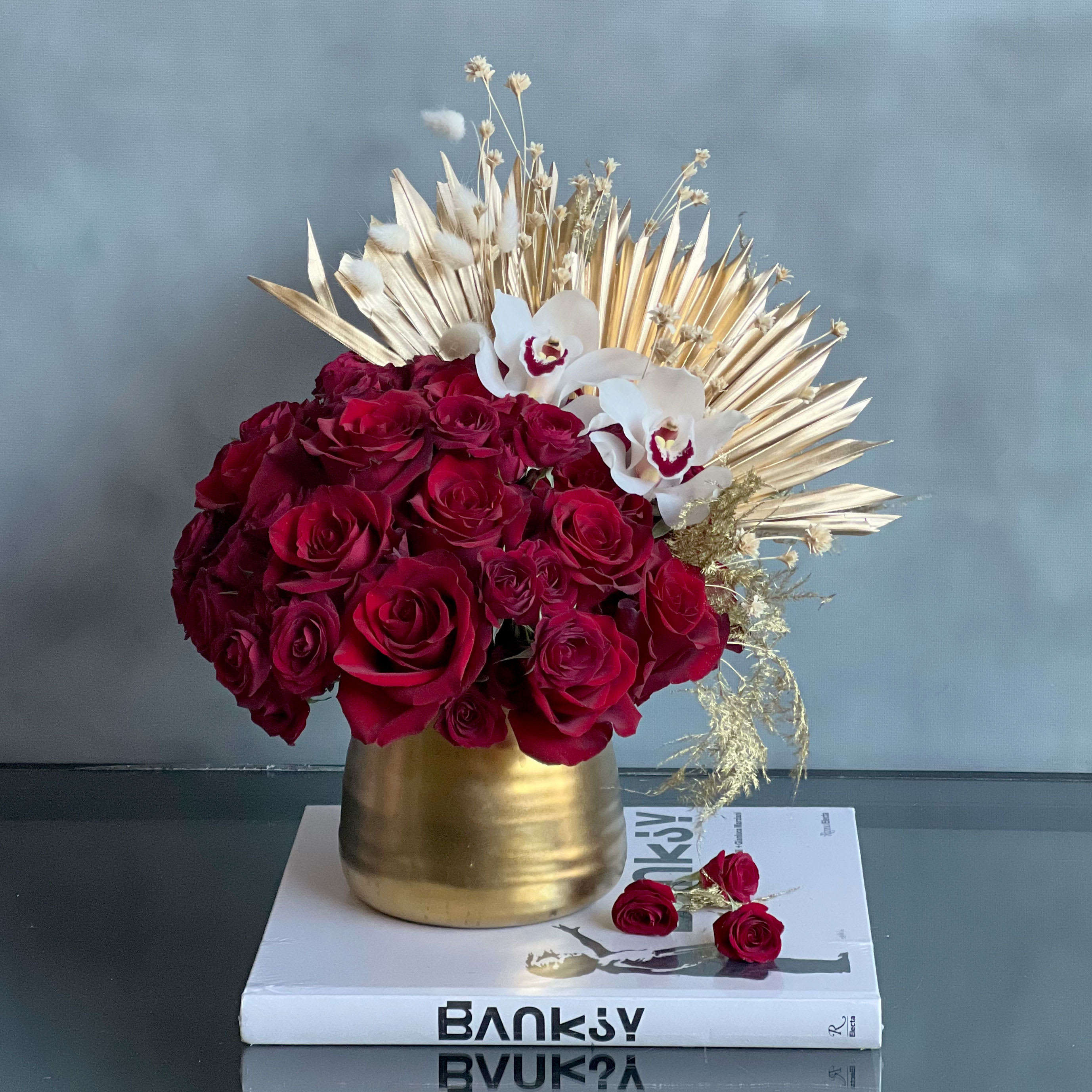 Golden Gate Roses - Pasadena Florist  - Our modern and simplistic &quot;Golden Gate Roses&quot; bring in an elegant touch of sophistication. In this arrangement we have various types of red Roses such as, Spray Roses and regular Roses. That are then accented with two Orchids and Golden Dry elements placed within a Golden Vase.   Measurement:  Vase: 4 x 4 Arrangement: 13 W x 13 T  