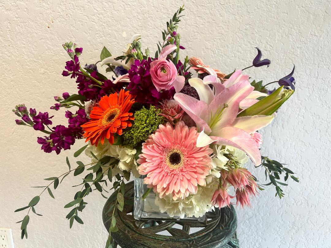 CFE171 CFE171 - A low modern arrangement of high end blooms such as lilies, roses and hydrangea in pinks and purples.