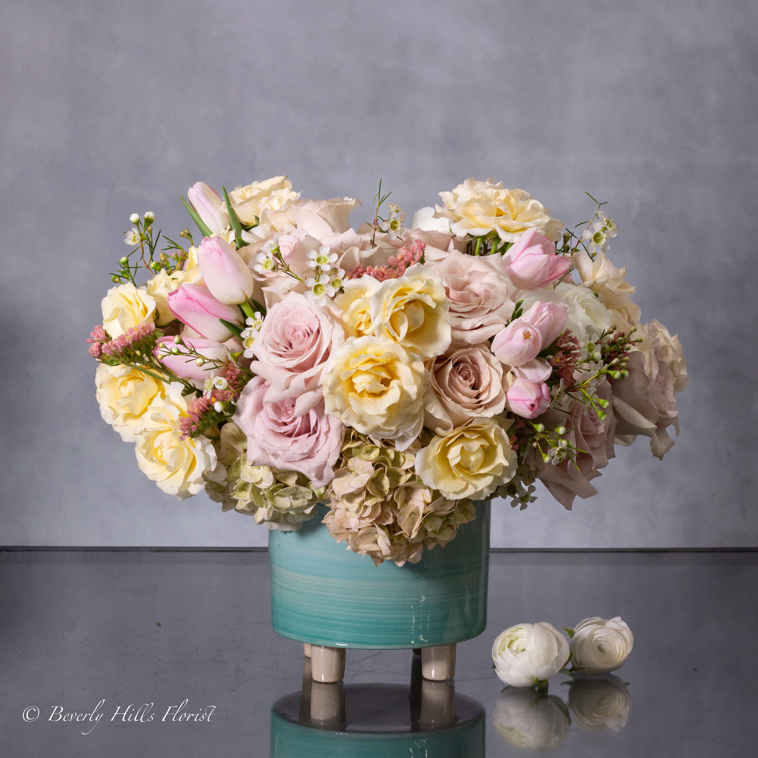 Aqua - Pasadena Florist - For a modern, soft, and feminine touch, our same-day delivery features an elegant aqua vase filled with a delicate combination of cream and pale pink flowers. This arrangement exudes a sense of grace and sophistication, perfect for brightening up any space with its gentle hues.  Measuring approximately 12&quot; round, this floral display is curated to bring a sense of tranquility and elegance to the recipient. With its contemporary aesthetic and soothing color palette, it serves as a lovely expression of care and appreciation for any occasion.