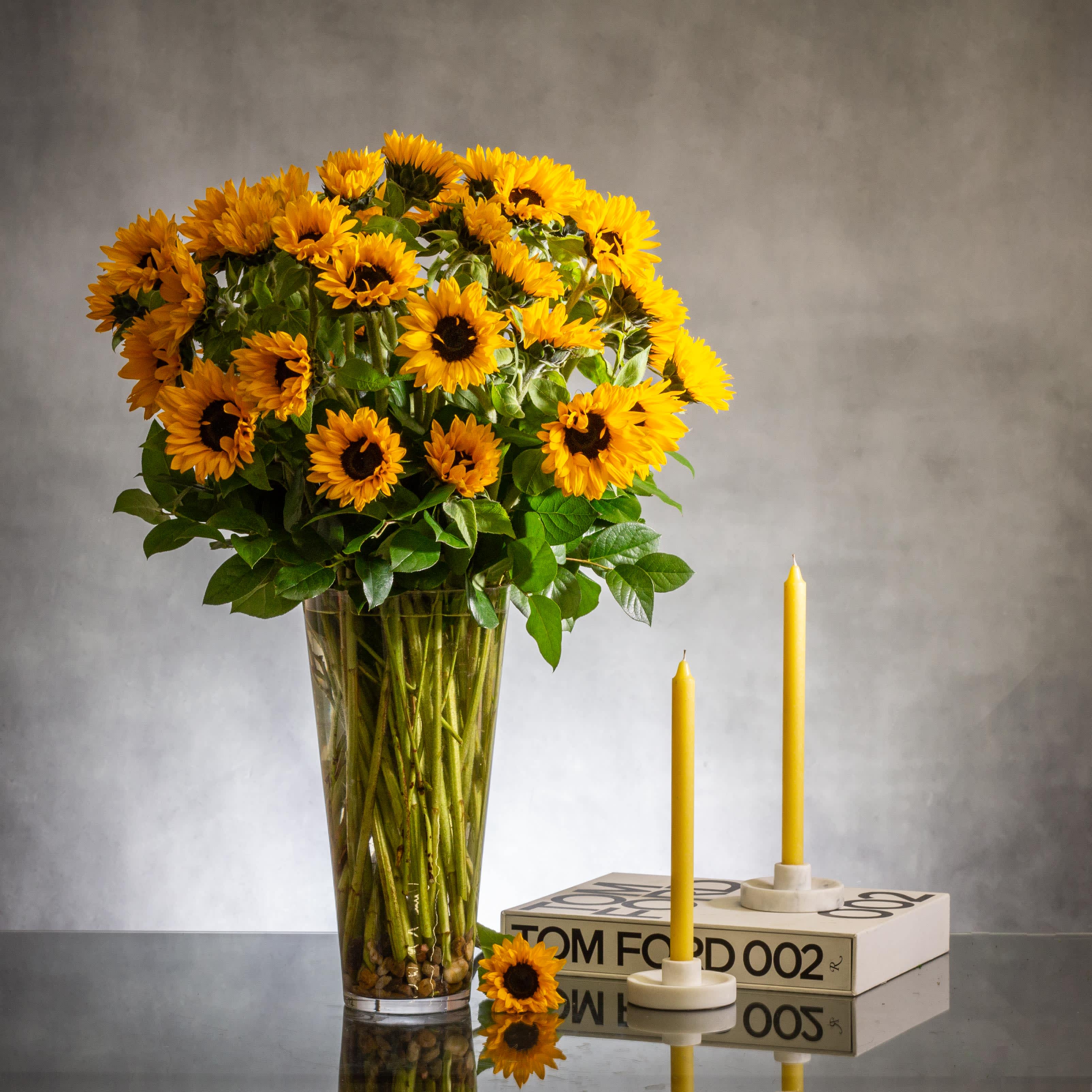 Falling for you - Pasadena Florist  - Beverly Hills Florist Presents for Same Day Delivery A stunning arrangement featuring vibrant sunflowers displayed in a tall glass vase would create a striking centerpiece. Sunflowers are known for their bright yellow petals surrounding a dark center, symbolizing adoration, loyalty, and longevity. Placed in a clear glass vase, these sunflowers would stand tall and proud, catching the sunlight and spreading cheer in any room. A simple yet beautiful choice for brightening up any space.  Approx 32&quot; Tall 