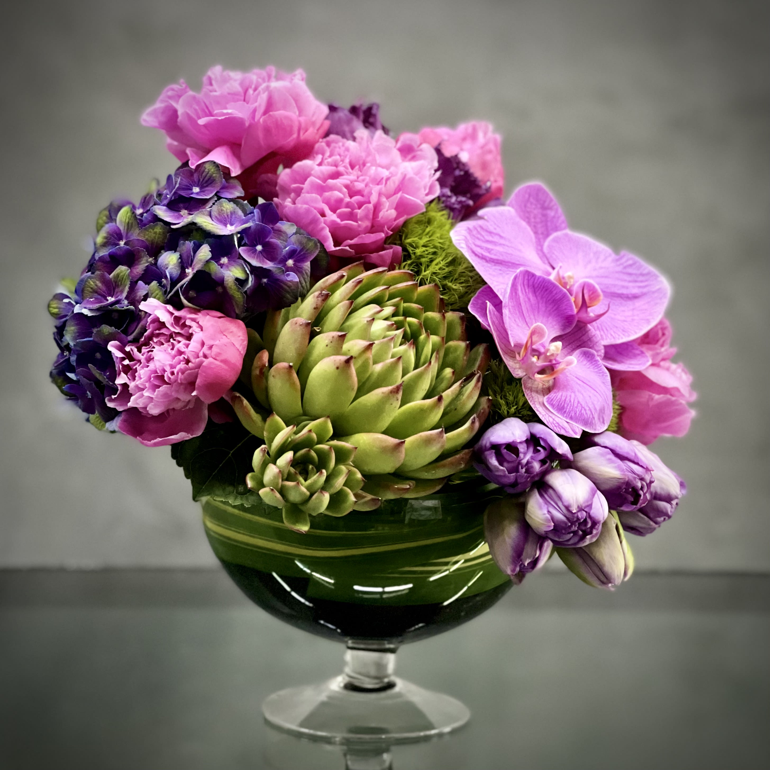 Blooming Beauty - Pasadena Florist - This striking floral arrangement designed by one of our talented designers consists of peonies, orchids, tulips, succulent and purple hydrangeas all nested in a glass pedestal bowl. Its simple, beautiful and elegant and perfect for occasions like birthday, special someone, thank you and get well.