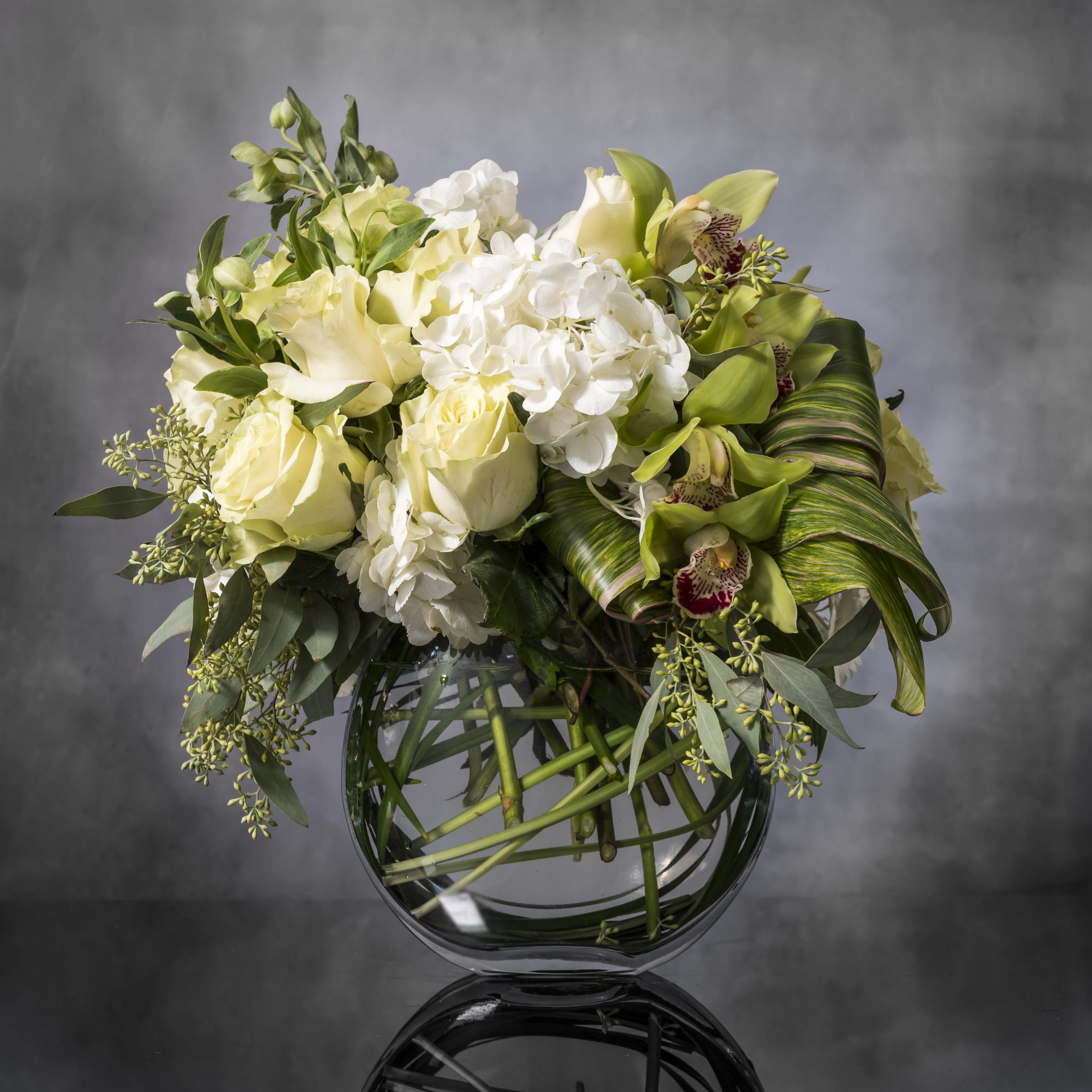 Precious Petals - Pasadena Florist - With a passion for luxurious classics, we've paired posh Cream Roses with Verdant Orchids in this elegant arrangement. Varying shades of green adds dimension to the creamy, crisp coloring of the roses and seasonal bloom accents. A perfect design for any décor or occasion.  Standard as shown   