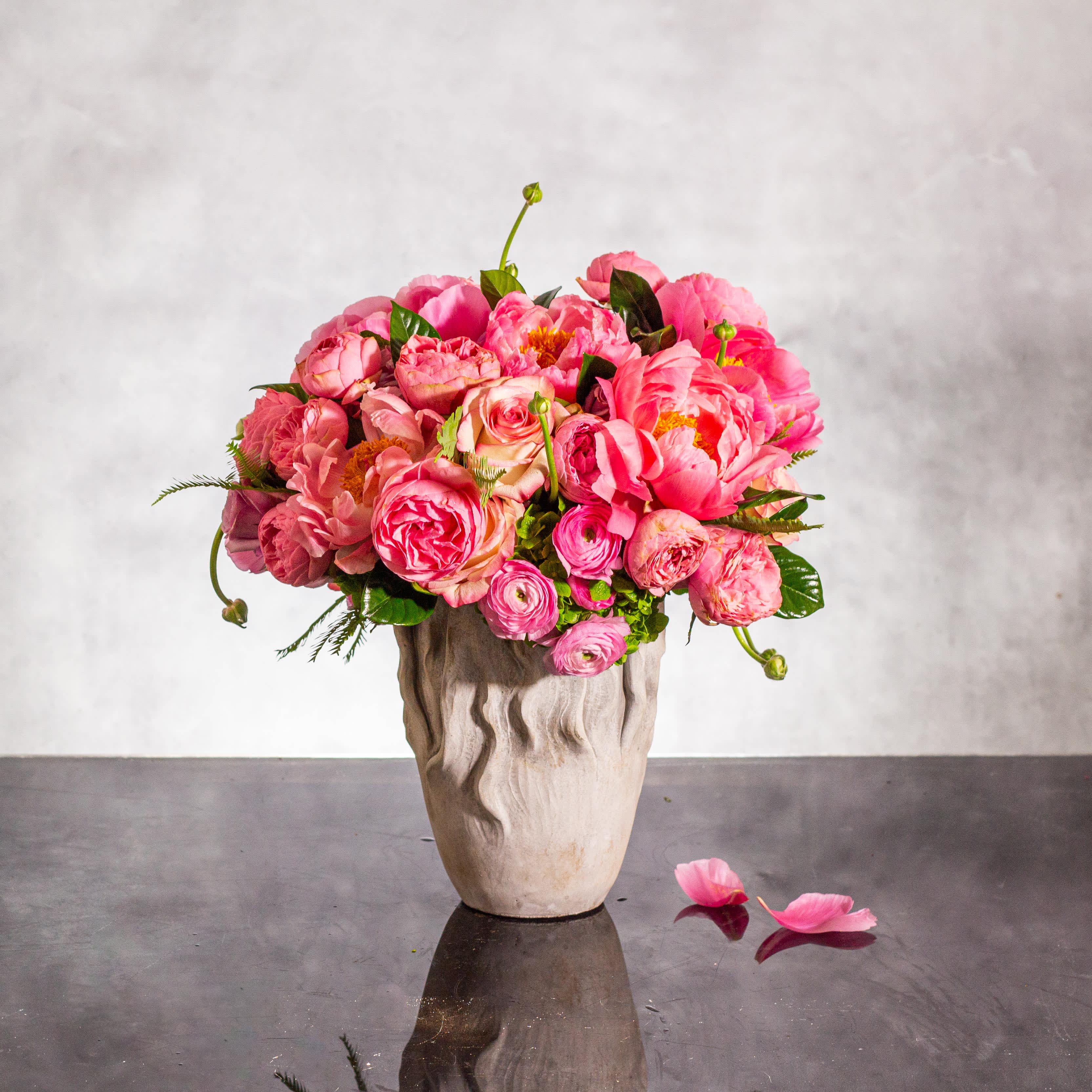 Harmony in Petals - Pasadena Florist - Indulge in a harmonious symphony of natural beauty with our exquisite floral arrangement, &quot;Blooming Elegance.&quot; Revel in the allure of beautifully opened peonies, variegated two-tone roses, and the unique addition of binoculars, all artfully arranged in a modern ceramic container. Standing at a grand 14 inches tall, this display exudes sophistication and charm.  The open peonies add a touch of timeless elegance, while the variegated two-tone roses bring a modern twist to the ensemble. The inclusion of binoculars not only adds a surprising element but also symbolizes the keen eye for detail within this arrangement. This display is a true masterpiece of floral artistry, captivating all who behold it with its beauty and grace. Add a touch of contemporary flair to any space with this radiant showcase of blooming brilliance.