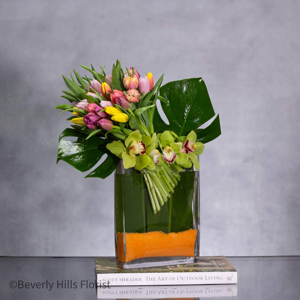 TULIPS IN SPRING  - spring Series - Pasadena Florist - Experience the convenience of same-day delivery with Beverly Hills Florist, ensuring that your tulip arrangement arrives fresh and vibrant, ready to infuse any space with the spirit of spring. Whether it's to commemorate a special occasion or to add a touch of seasonal charm to your home, our tulip arrangements with orange sands are the perfect choice.  Approx. 18&quot; tall in a 10&quot; Tall X 8&quot; Wide glass Vase 