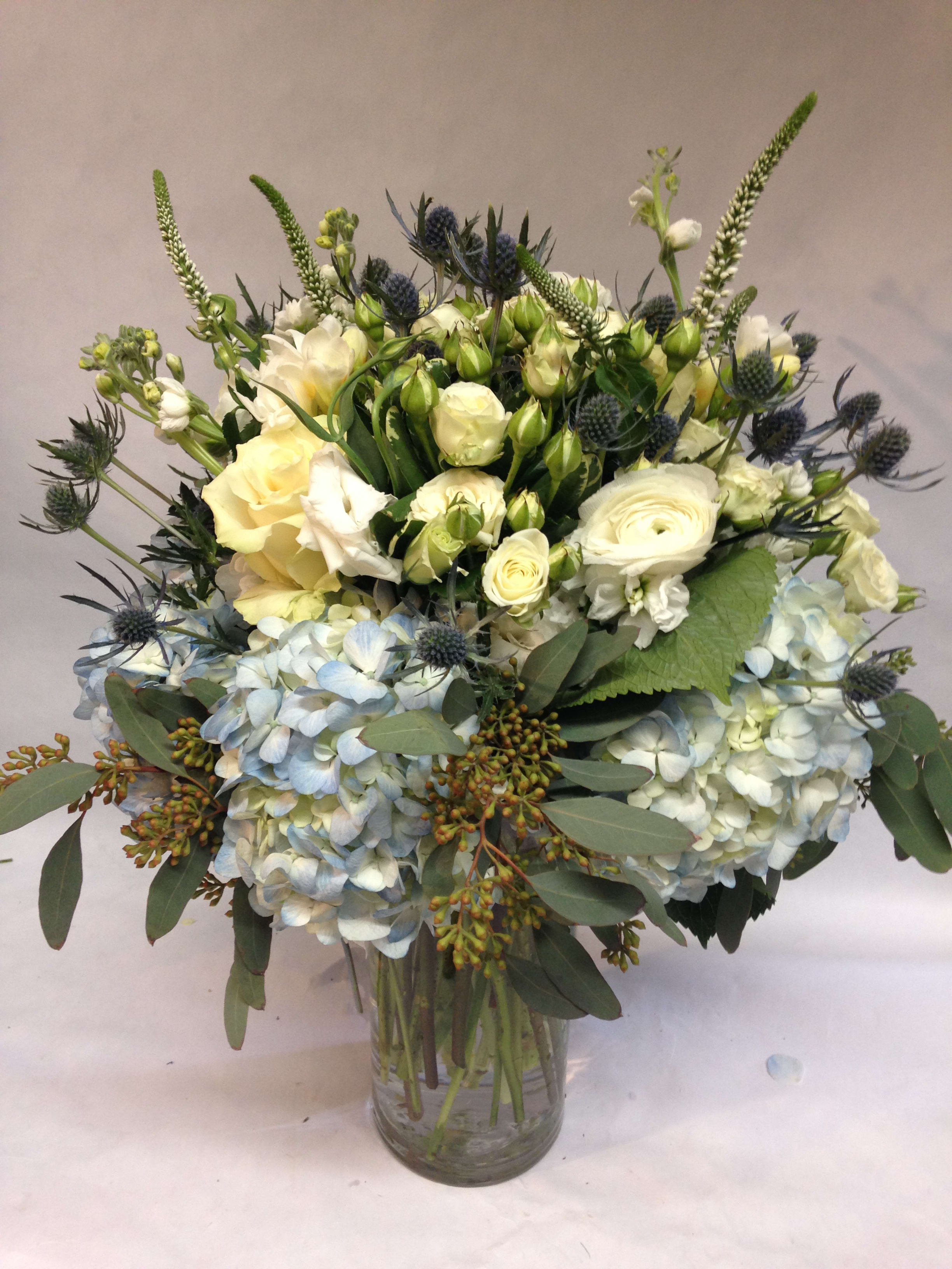 Brush of Blue Arrangement Brush of Blue Arrangement - An elegant and lovely arrangement with just a hint of blue. Featuring spray roses, thistle, hydrangea, veronica, lisianthus, and greenery. (Some flowers may be subject to change depending on the season. We will contact you with available flower substitutions; please contact us with specific questions if you are concerned with flower availability, thanks!) Featured Arrangement: $235.00