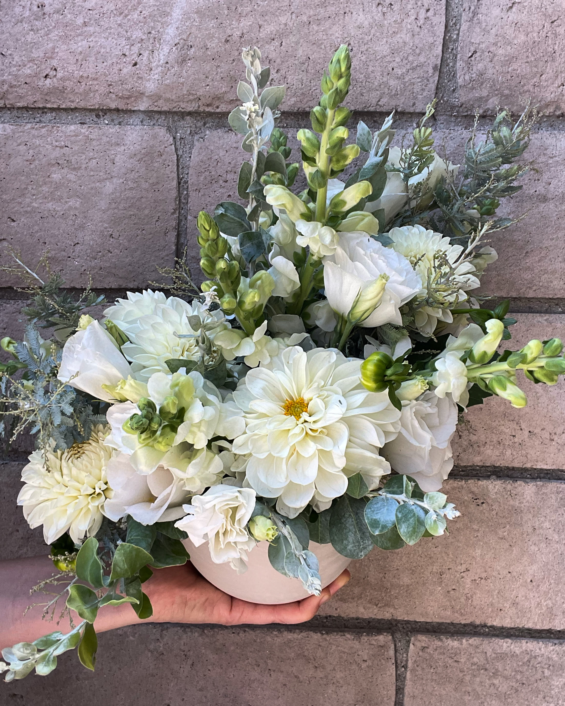 White Rabbit  - A light and fluffy arrangement for lovers of white flowers. Dahlia, Lisianthus, Snapdragons, Acacia (seasonal) and fragrant Eucalyptus come together in a shapely ceramic vase which gift the illusion of the flowers &quot;jumping&quot; out. Delightful and crisp, sure to please. 