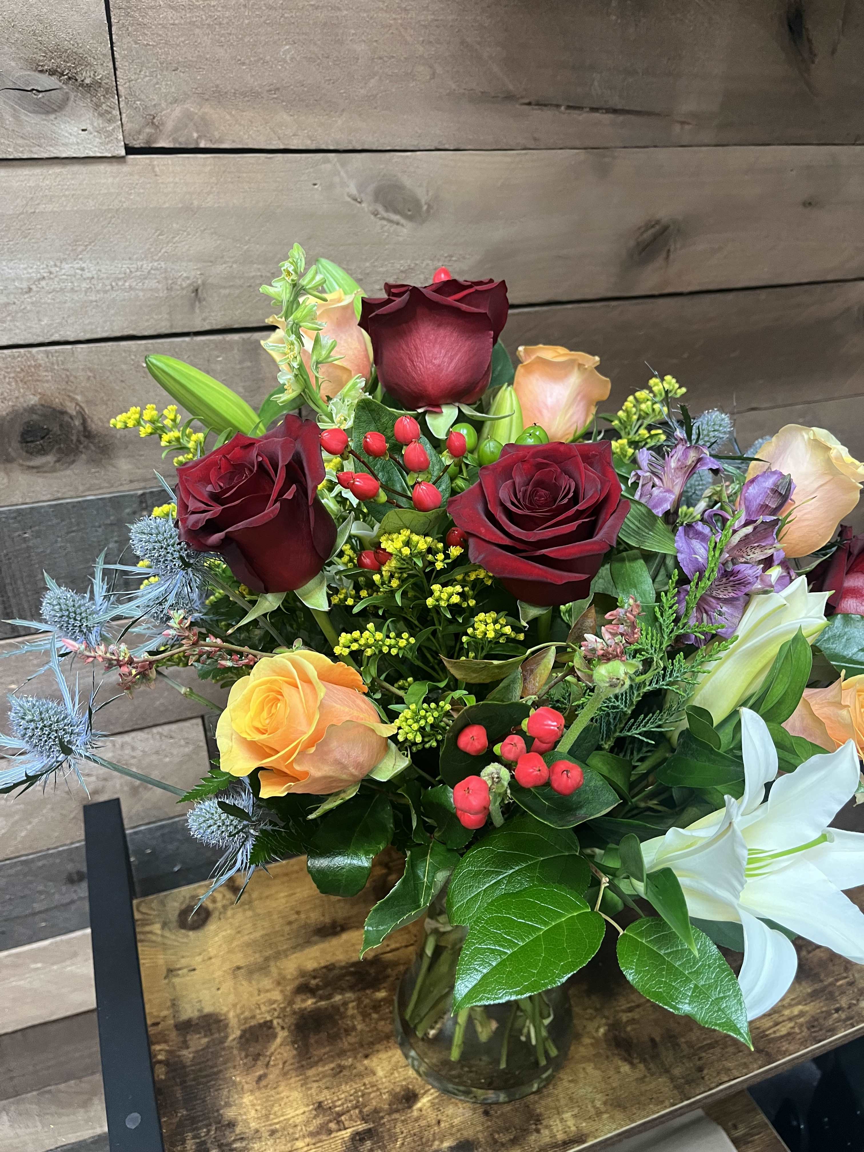 Timeless Elegance Timeless Elegance - The "Timeless Elegance" arrangement blends red and orange roses with lilies, solidago, and stock, accented by verdant greenery for a sophisticated and vibrant display.
