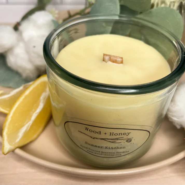 Wood and Honey Summer Kitchen Candle Wood and Honey Summer Kitchen Candle - Bursting with freshness, bright lemongrass and juicy lime top notes meld seamlessly with sweet middle notes of black currant and earthy touches of sage and thyme. Whether you're looking to unwind after a long day or boost your energy in the morning. Ideal for a “clean kitchen” aroma. This candle is created using bees wax in a fully recyclable jar. The fresh cut wood lid creates no plastic waste. Beeswax Candles are the healthiest choice in candles. Many candles on the market today, and yes, even some soy, are blended with other bi-products that are harmful to you and the environment. You wouldn't believe how many chemicals are found in the typical store bought candle. Made from the caps of bee honeycombs, beeswax candles burn clean, have a very long burn time in comparison with other waxes and actually help to purify the air by releasing negative ions. These negative ions can bind with toxins and help remove them from the air. Therefore, beeswax candles actually help to neutralize airborne allergens and purify the air. Beeswax candles are an excellent choice for burning in your home or office for this reason.