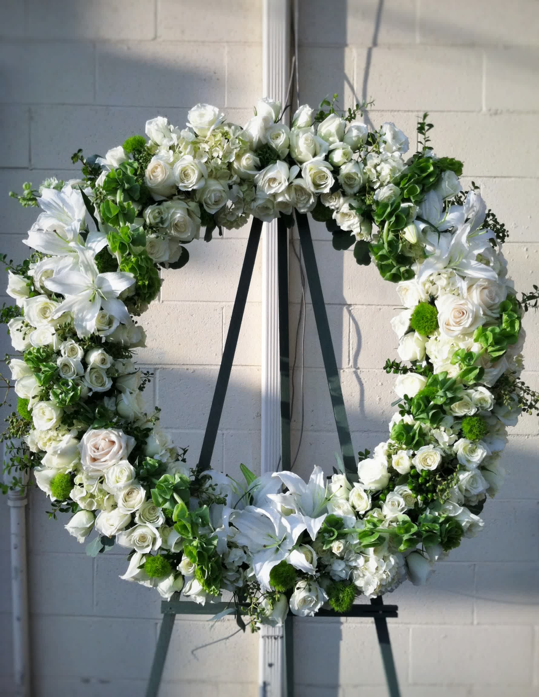 Land of Dreams Wreath - A wreath with with a white and green theme: white roses, lilies, hydrangea, and bells of Ireland. 