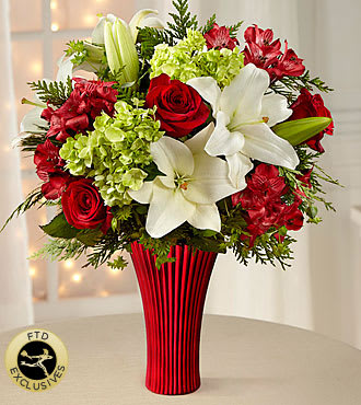 The FTD® Holiday Celebrations™ Bouquet - Blooming with Christmas cheer and holiday elegance, this stunning yuletide flower bouquet is a gorgeous gift of winter wonder. Red roses, carnations, and Peruvian lilies set the back drop for the white Asiatic lilies to pop, arranged amongst green mini hydrangea and holiday greens, perfectly set in a keepsake metallic red glass flared vase.  Container is discontinued, we will sub in a similar container