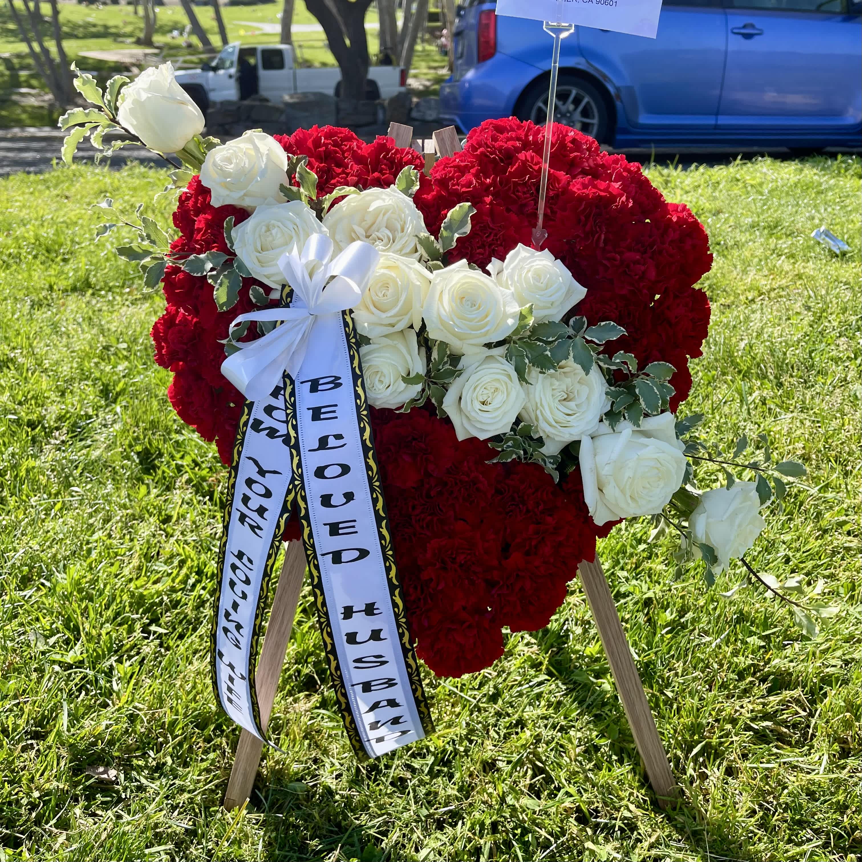 Forever Love Forever Love - A beautiful all-red heart of carnations accentuated with white roses and greenery. Easel and optional banner included. If a banner is required, please leave the message in the special instructions.