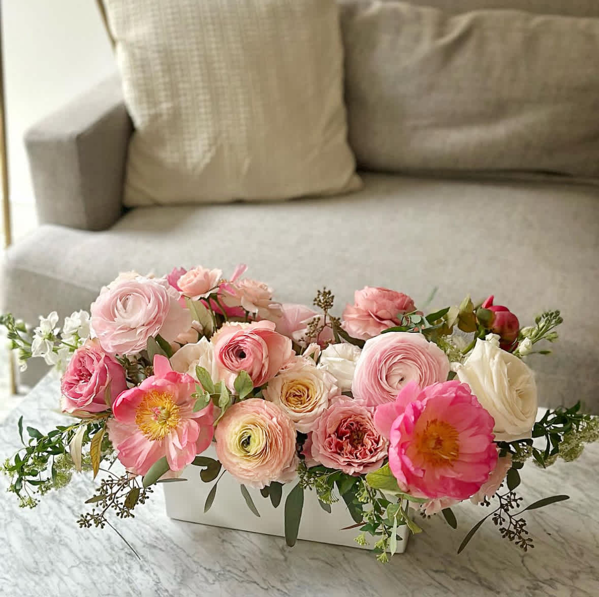 Garden Romance Vase - The &quot;Garden Romance Vase&quot; is a breathtaking arrangement that exudes elegance and charm. Featuring an assortment of pastel blooms and lush greenery, this wide rectangular vase arrangement is perfect for creating a romantic ambiance or celebrating special occasions.  Arrangement Details: Main Flowers: Ranunculus, Garden Roses, Peonies, Lisianthus, Stock, Eucalyptus Container: Elegant wide rectangular white vase Approximate Dimensions: 24&quot;W x 12&quot;H
