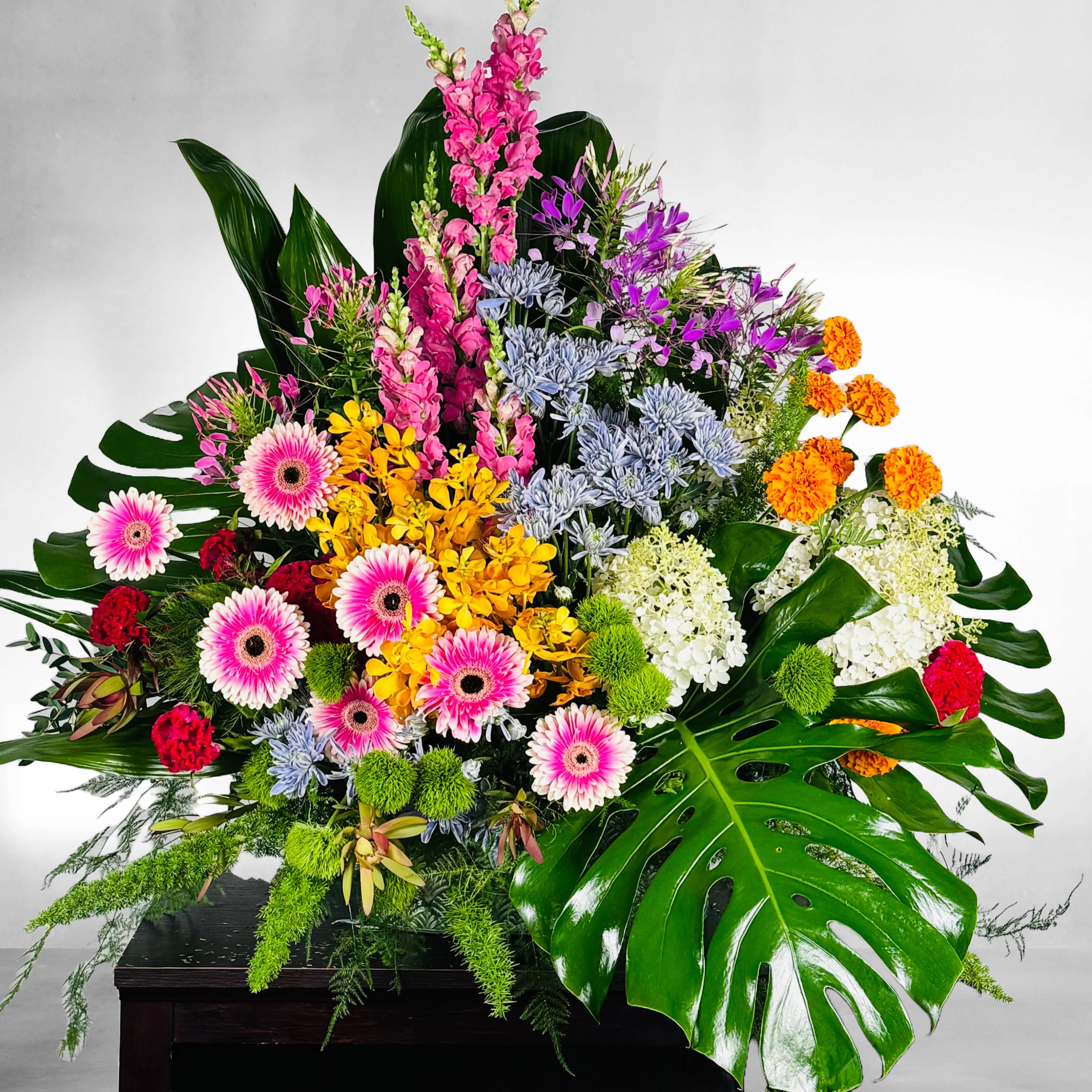 Everlasting Memory - A full celebration of colors, this multi-flower and bright table top arrangement is representative of a life lived to its fullest. Colors and flowers may change based off of season and availability. 