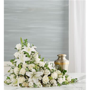 Asymetrical Cremation Arrangement- All White - Our all-white arrangement sends a heartfelt message of hope to those coping with loss. Handcrafted in an elegant asymmetrical design, it’s a beautiful tribute to honor the life of someone very special. One-sided arrangement of white roses, Asiatic lilies, snapdragon, carnations, stock and monte casino; accented with assorted greenery Intended to be sent to the memorial service Large arrangement measures approximately 24&quot;H x 29&quot;W Small arrangement measures approximately 20&quot;H x 27&quot;W Our florists hand-design each arrangement, so colors and varieties may vary due to local availability To ensure lasting beauty, Asiatic lilies may arrive in bud form and will fully bloom over the next few days
