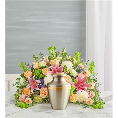 Crescent Cremation Arrangement- Pastel - Express your heartfelt condolences with a beautiful floral tribute. Our crescent shaped design is handcrafted from a soothing cascade of pastel blooms to honor a loved one in a meaningful way. One-sided arrangement of peach roses, pink Oriental lilies, snapdragon and carnations, Bells of Ireland lime green carnations, green button poms, white football mums, purple waxflower and monte casino; accented with baby’s breath and assorted greenery Intended to be sent to the memorial service; urn or framed photograph can be placed in front center of the arrangement Large arrangement measures approximately 21&quot;H x 30&quot;W Small arrangement measures approximately 17&quot;H x 25&quot;W Our florists hand-design each arrangement, so colors and varieties may vary due to local availability To ensure lasting beauty, Oriental lilies may arrive in bud form and will fully bloom over the next few days