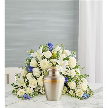 Crescent Cremation Arrangement- Blue And White - Express your heartfelt condolences with a beautiful floral tribute. Our blue and white crescent shaped design is handcrafted from a soothing cascade of blooms to honor a loved one in a meaningful way. One-sided arrangement of blue delphinium, white roses, Oriental lilies, football mums, button poms, carnations, stock, waxflower and monte casino; accented with baby’s breath and assorted greenery Intended to be sent to the memorial service; urn or framed photograph can be placed in the front center of the arrangement Large arrangement measures approximately 21&quot;H x 30&quot;W Small arrangement measures approximately 17&quot;H x 25&quot;W Our florists hand-design each arrangement, so colors and varieties may vary due to local availability To ensure lasting beauty, Oriental lilies may arrive in bud form and will fully bloom over the next few days