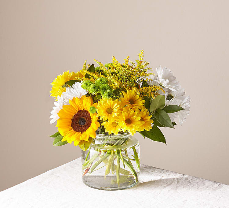 Hello Sunshine Hello Sunshine - Give a dose of sunshine in bloom. This stunning bouquet is teeming with rays of sunflowers, textured snapdragons and darling daisy poms to deliver the perfect pick–me–up for an occasion or as a treat to yourself.