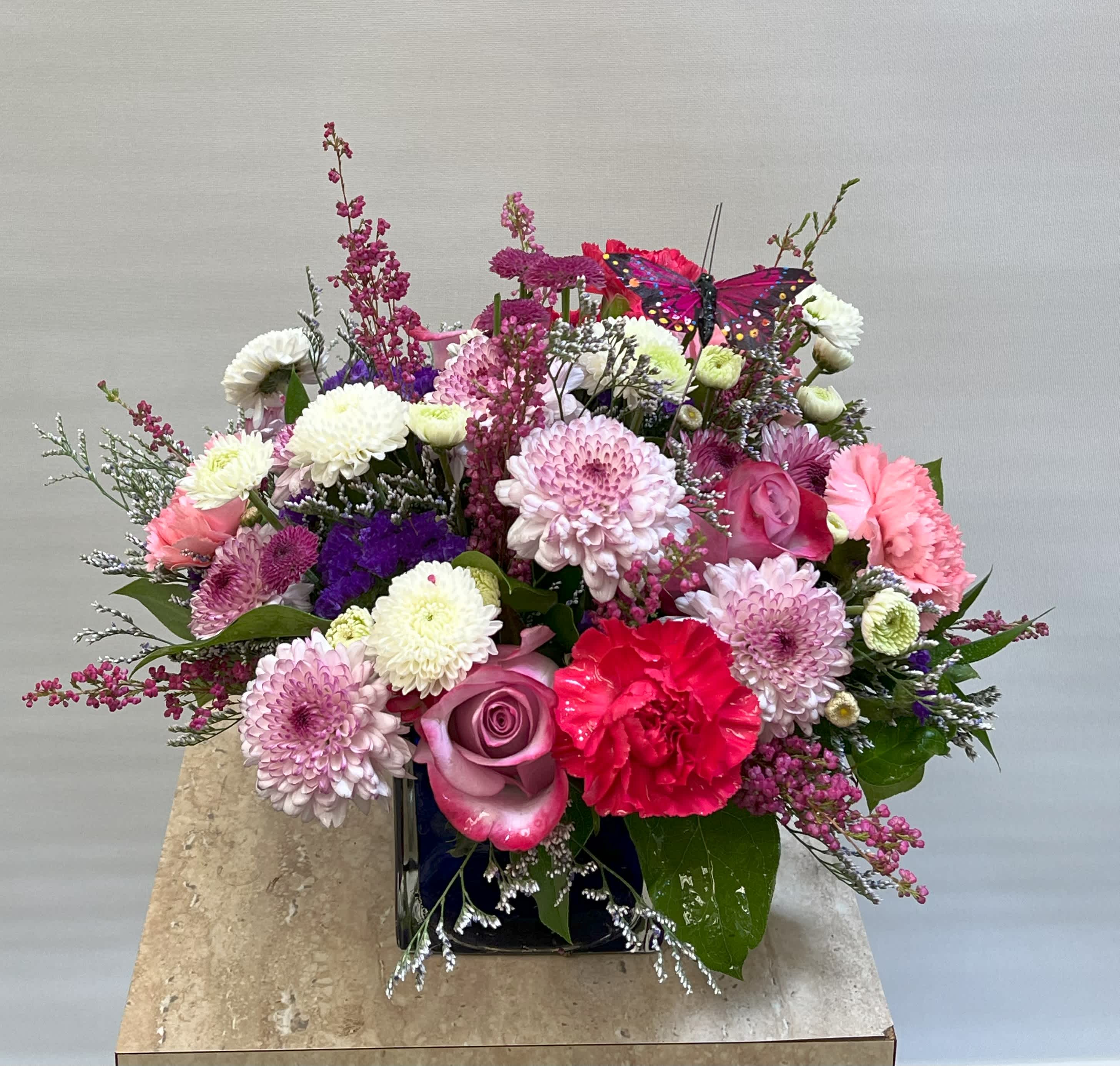 Purple Blooms  - A purple cubed vase with a variety of purple and pink flowers. 