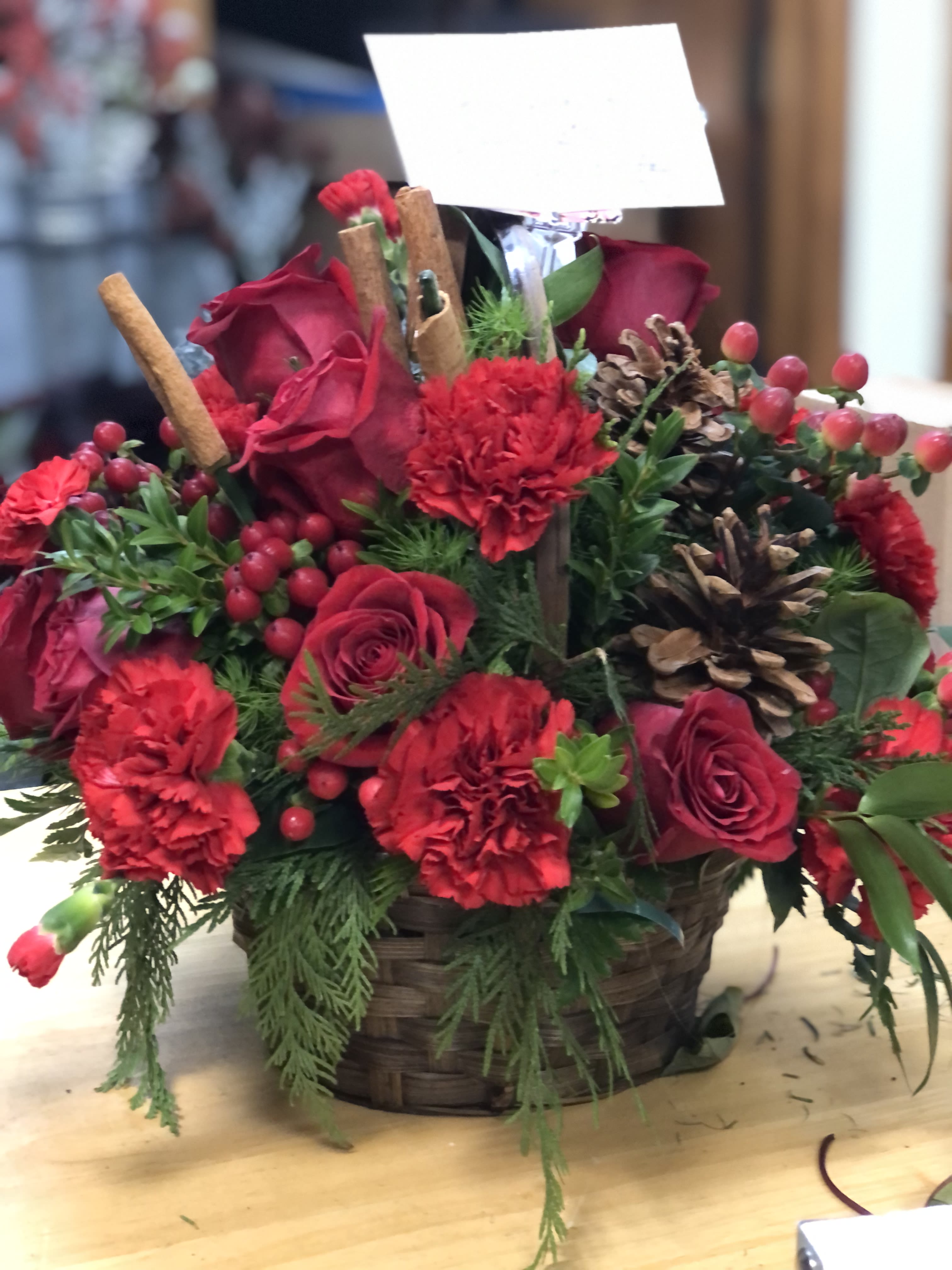 winter's delight - Red carnations, roses, pine cones and sprigs of cinnamon in a lovely basket of evergreens  $50.00+