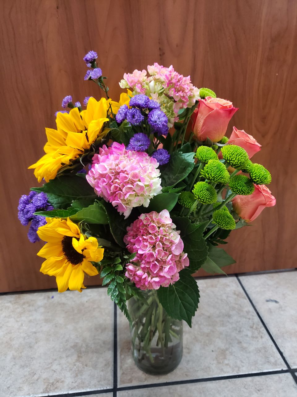 fall in love - beautiful arragmanet with   3 sunflowers, 3 pink hydrangeas, 3 oranges roses, 3 stem of green button, purple monte casino and a  ginger clear base,    