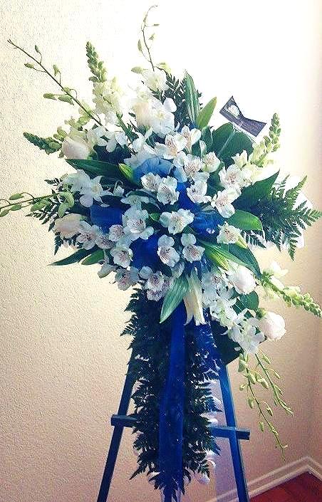 Orchid & Lily Sympathy Cross Orchid & Lily Sympathy Cross - Sympathy Cross composed of White Dendrobium Orchids, Lilies, & Alstroemeria. Arranged on a ribbon ruffled cross lined with foliage and accented with dark blue tulle. Measures approx. 30"-34" tall. Stand included.