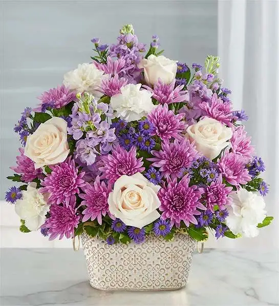 Loving Remembrance Lavender and White Loving Remembrance Lavender and White - Celebrate the life of a loved one with our beautiful floral tribute. A mix of blooms in soothing shades is a symbol of enduring love. Designed in our Remembrance Cachepot, featuring an embossed pattern and finished with a gold brushed ivory surface.