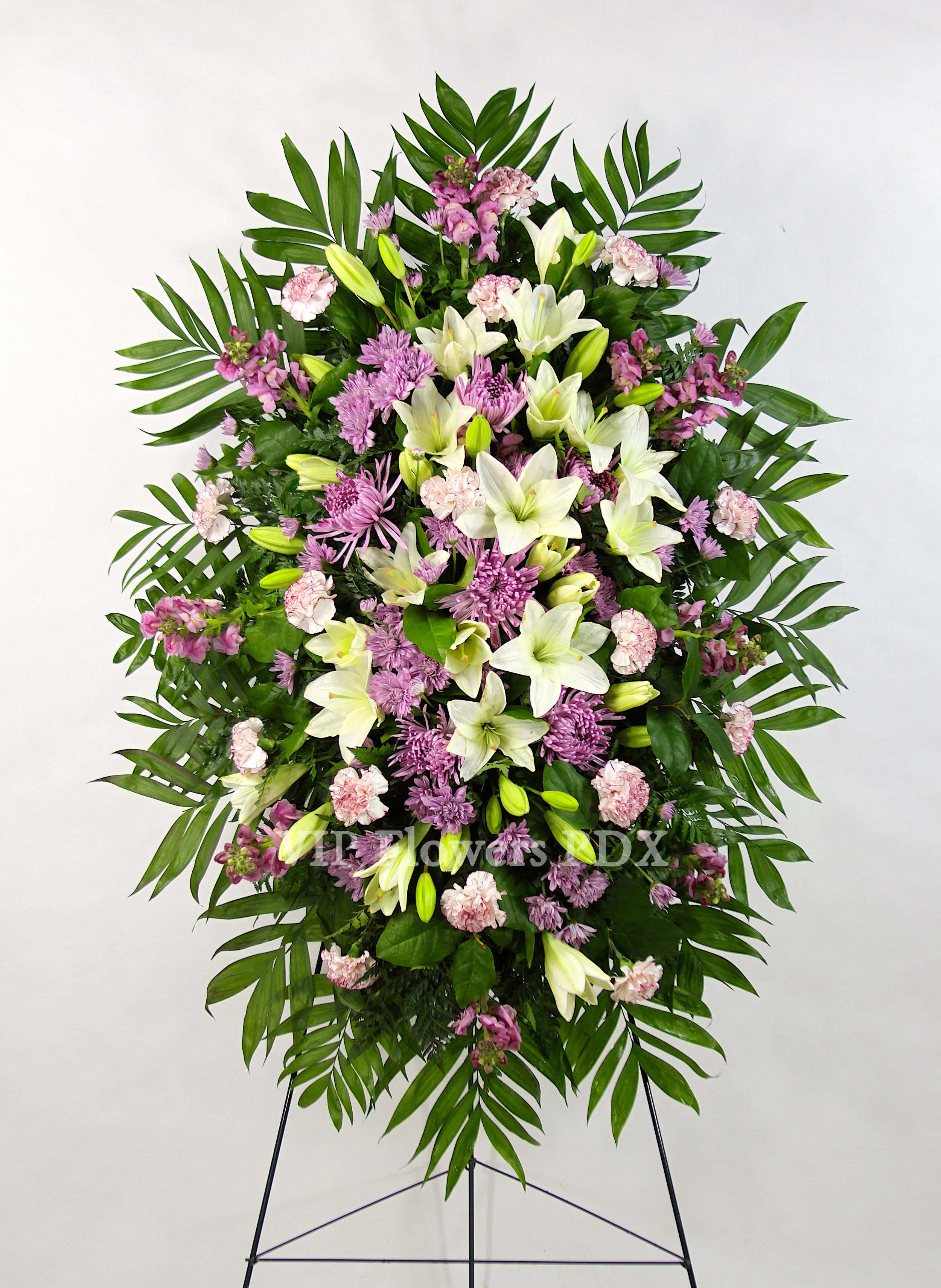 Purple &amp; White Spray - Flowers Included:  Lilies Carnations Chrysanthemums Mums Stock Seasonal Flowers Seasonal Greens       Substitutions may be necessary to ensure your arrangement or specialty gift is delivered in a timely manner. The utmost care and attention is given to your order to ensure that it is as similar as possible to the requested item (Please note that some flowers and colors may vary due to seasonality.)