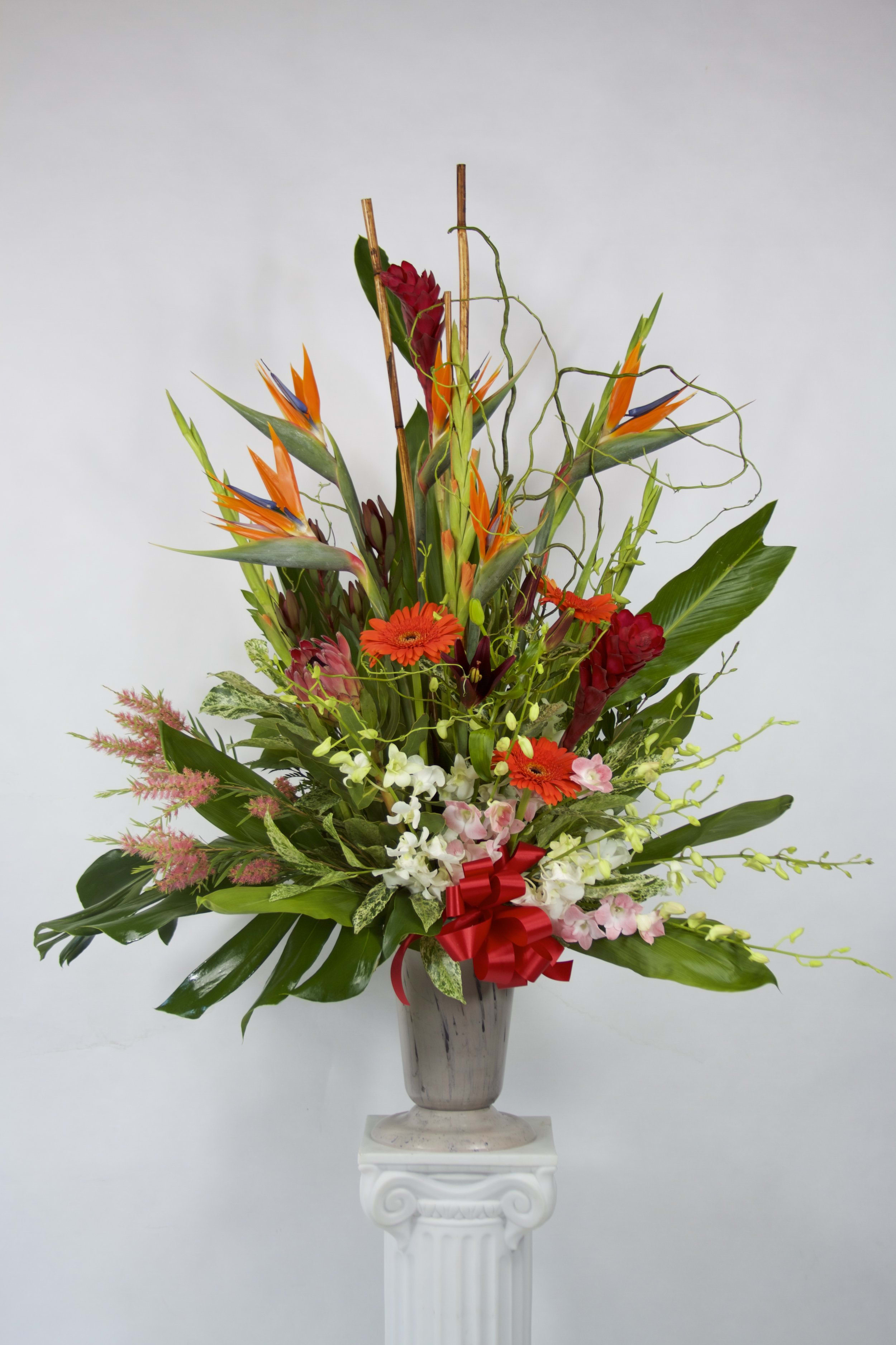 Pillar of Truth - A flower arrangement that truly speaks volumes! Exotic inspired bouquet is hand-arranged using the freshest birds of paradise, gerberas, gladiolus, white &amp; pink orchids, ginger, gathered together into a grey vase/container. Send this delightful surprise to someone you care about and help them celebrate the carefree beauty of exotics!  Flowers included:  Birds of Paradise Gerberas (Daisy type) White &amp; Pink Orchids Ginger Gladiolus Curly Willow Greens          Substitutions may be necessary to ensure your arrangement or specialty gift is delivered in a timely manner. The utmost care and attention is given to your order to ensure that it is as similar as possible to the requested item (Please note that some flowers and colors may vary due to seasonality.)