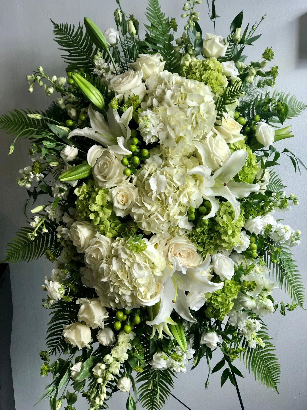 The Divinity by Simply Fresh Flowers (requires 72 hours notice) - The Divinity is an elegant, white &amp; green standing spray comprised of oriental lilies, hydrangea, roses, delphinium, lisianthus, stock, hypericum berries &amp; seasonal accent blooms.  Simply lovely! Please note: this design requires 72 hours notice.