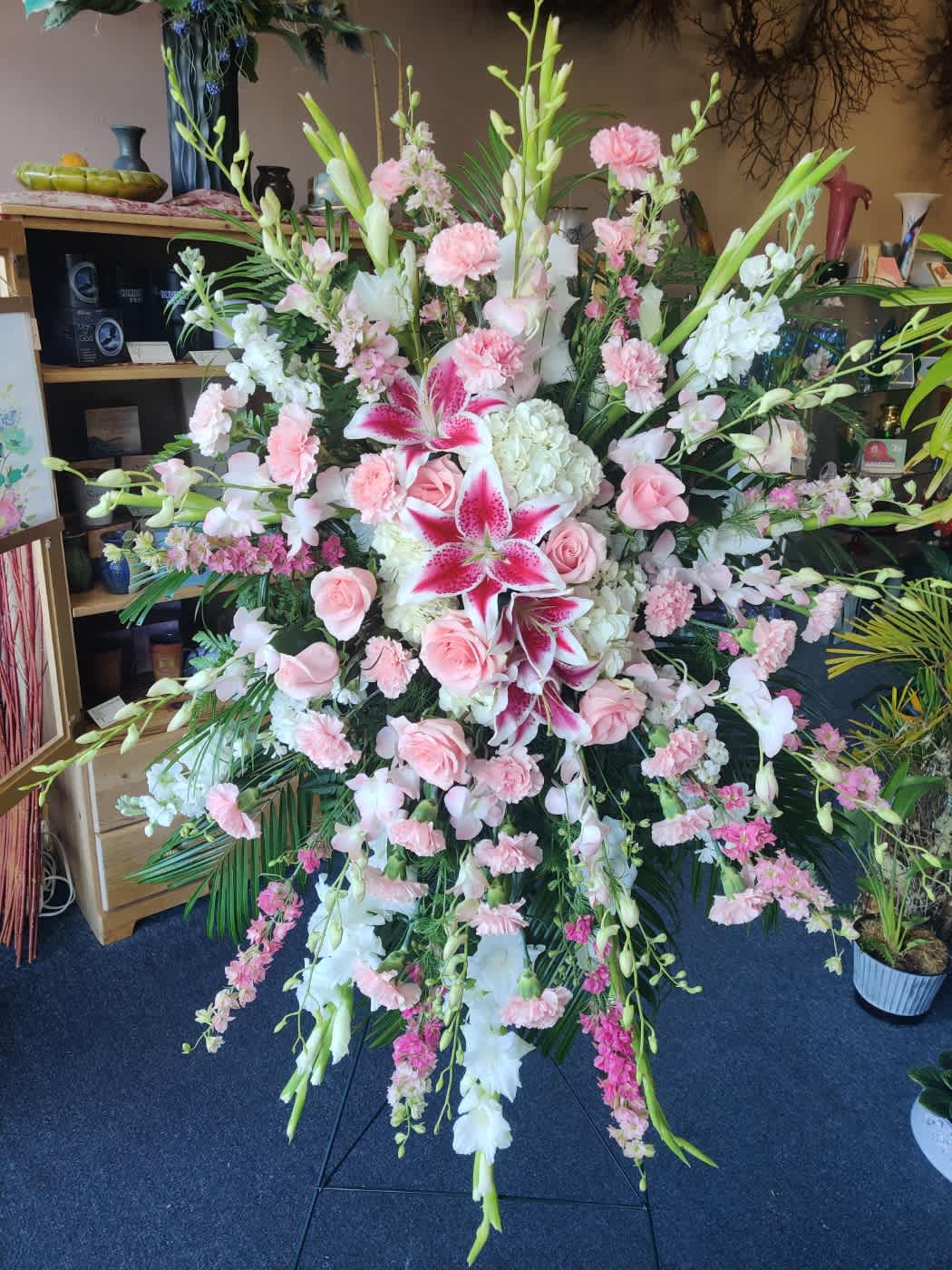 Pink Standing Easel - This beautiful standing easel contains Gladiolus, Larkspur, Stocks, Hydrangea, Stargazer lily, Roses, Carnations, and Greenery 