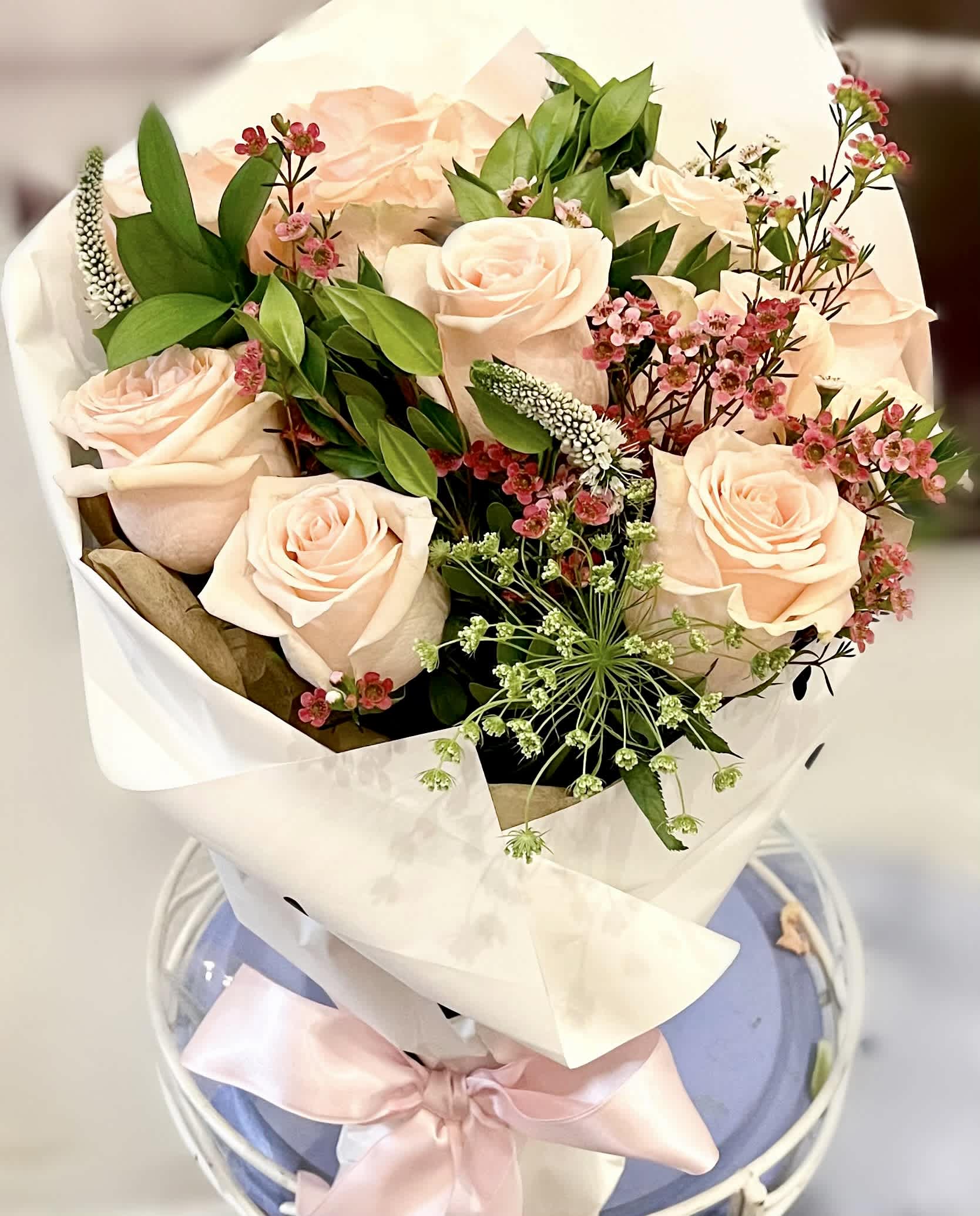 Paper Hearts : Mothers Day Flower Bouquets - A handheld bouquet with our premium handpicked garden variety roses in blush, accented  by an assortment of beautiful greenery. Presented in a white wrap with small hearts, and tied together with a blush satin ribbon. 