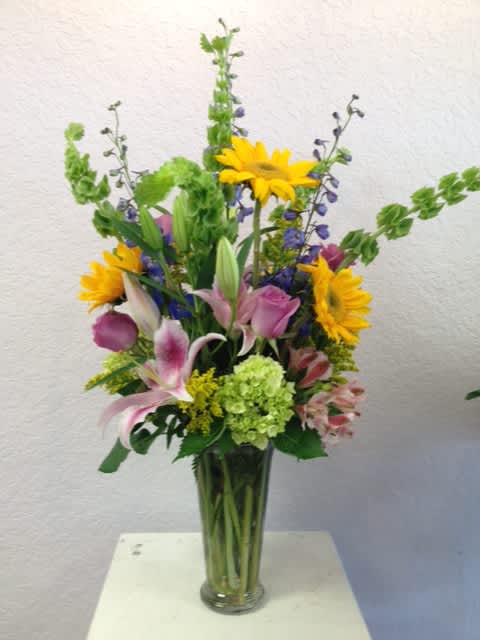 CFE103 CFE103 - A tall beautiful mixed arrangement of different flowers in vibrant tones such as lilies, roses, hydrangeas, bell of ireland and other seasonal blooms.