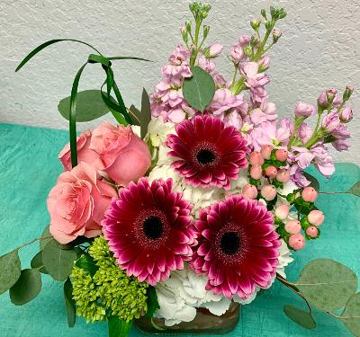 CFE119 CFE119 - A low compact arrangement of roses, gerber daises, hydrangeas and other flowers in pink and white tones.