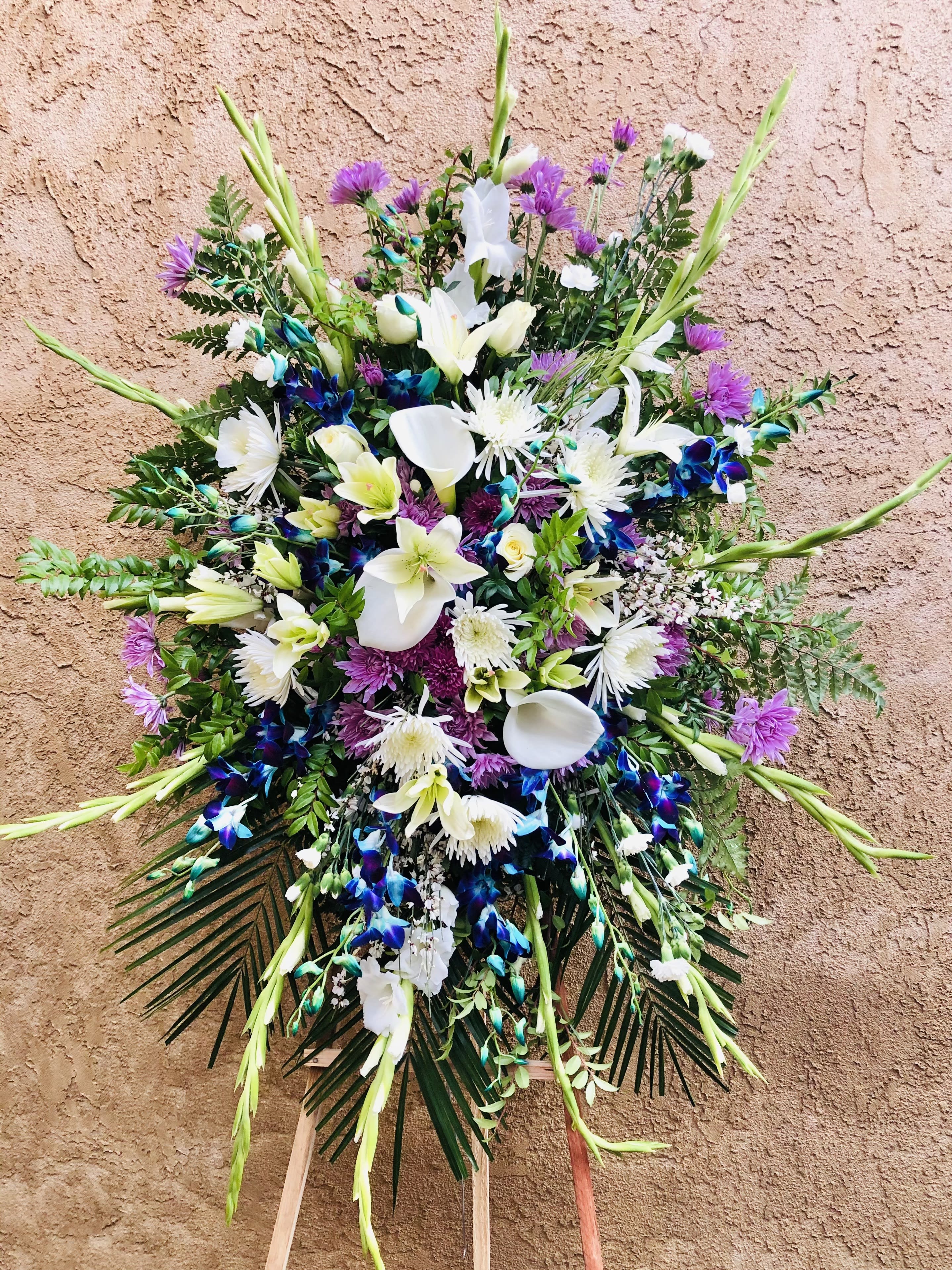 Bright Life - Beautiful blue and purple standing spray arrangement featuring calla lillies, mums, gladiolus, lilies and green leaf accents.