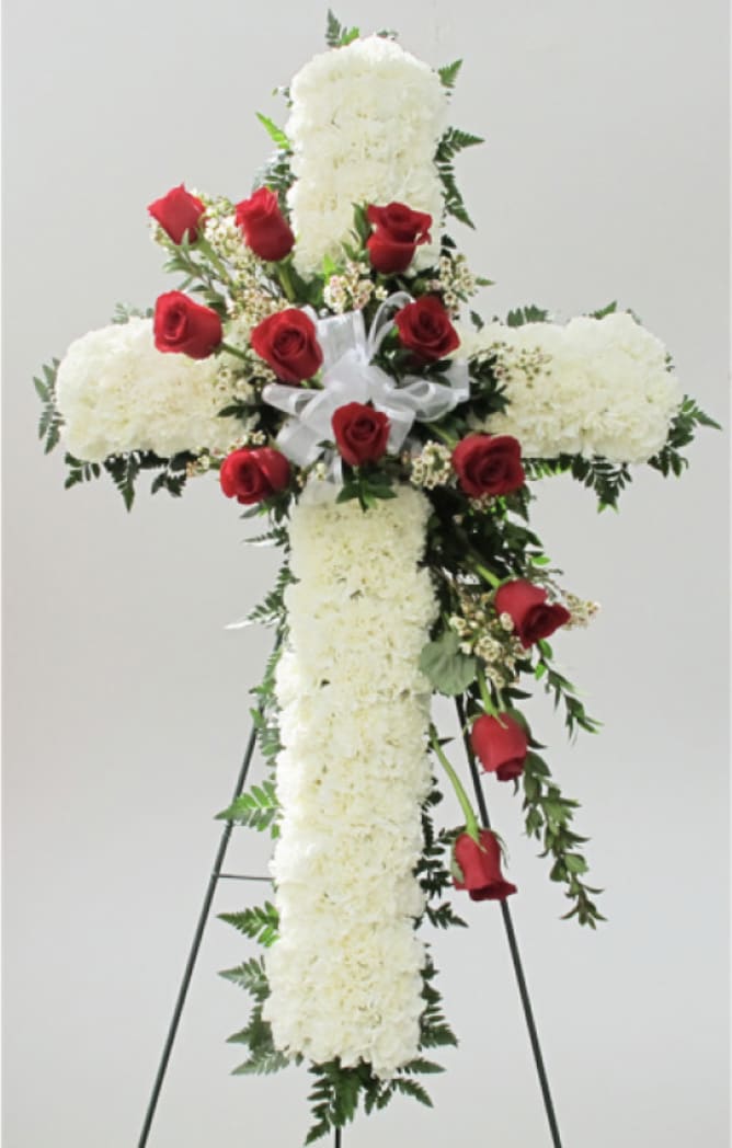 Floral Cross on Easel Floral Cross on Easel - The Floral Cross Easel is a symbol of love and faith to honor the deceased at their funeral or memorial service. Designed with white carnations, red roses, and lush greens Designed on a 30 inch tall cross form and delivered on a wire easel. We're able to design with your choice of color roses
