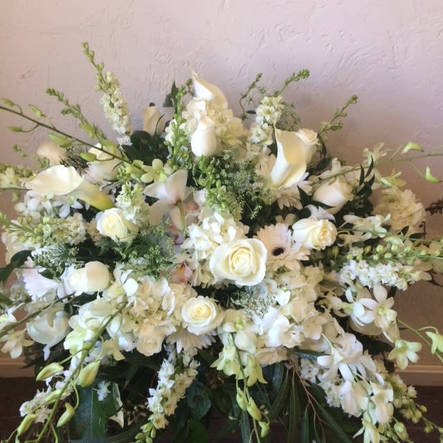 Cricket's Sincerity Casket Spray Cricket's Sincerity Casket Spray - This is a presentation of elegance and beauty. Lush white roses and orchids, snapp, stock are eye-catching and elegant in an arrangement of white hydrangea, larkspur, snapdragons, Queen Anne's Lace and assorted lush greens to create a lovely display **** Please note: 48 hour notice MAYBE REQUIRED We custom-design this arrangement using best-of-day seasonal flowers. This image is a general representation of its size and style and may not feature the exact flowers shown. Due to disruptions in the global supply chain and staff shortages, we may have to make last minute substitutions to your selected design. If we need to make significant changes we will call you first to get your approval*** Thank you for understanding.