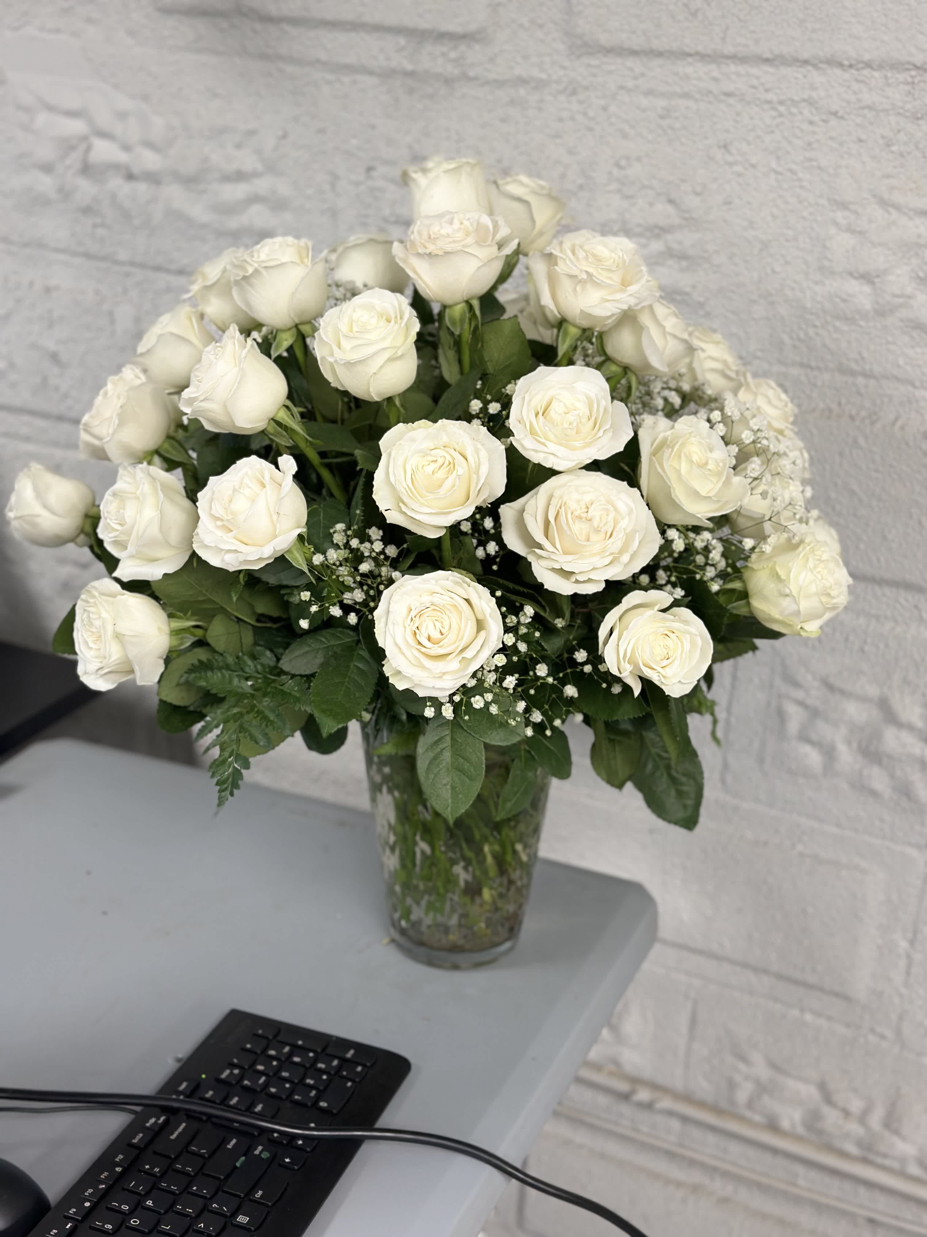 White Roses by the Dozen - Experience the celestial beauty of our breathtaking arrangement featuring of pristine white roses that embody purity, serenity, and divine elegance. Each delicate bloom is carefully selected for its flawless beauty and ethereal charm, creating a stunning display that exudes grace and sophistication.