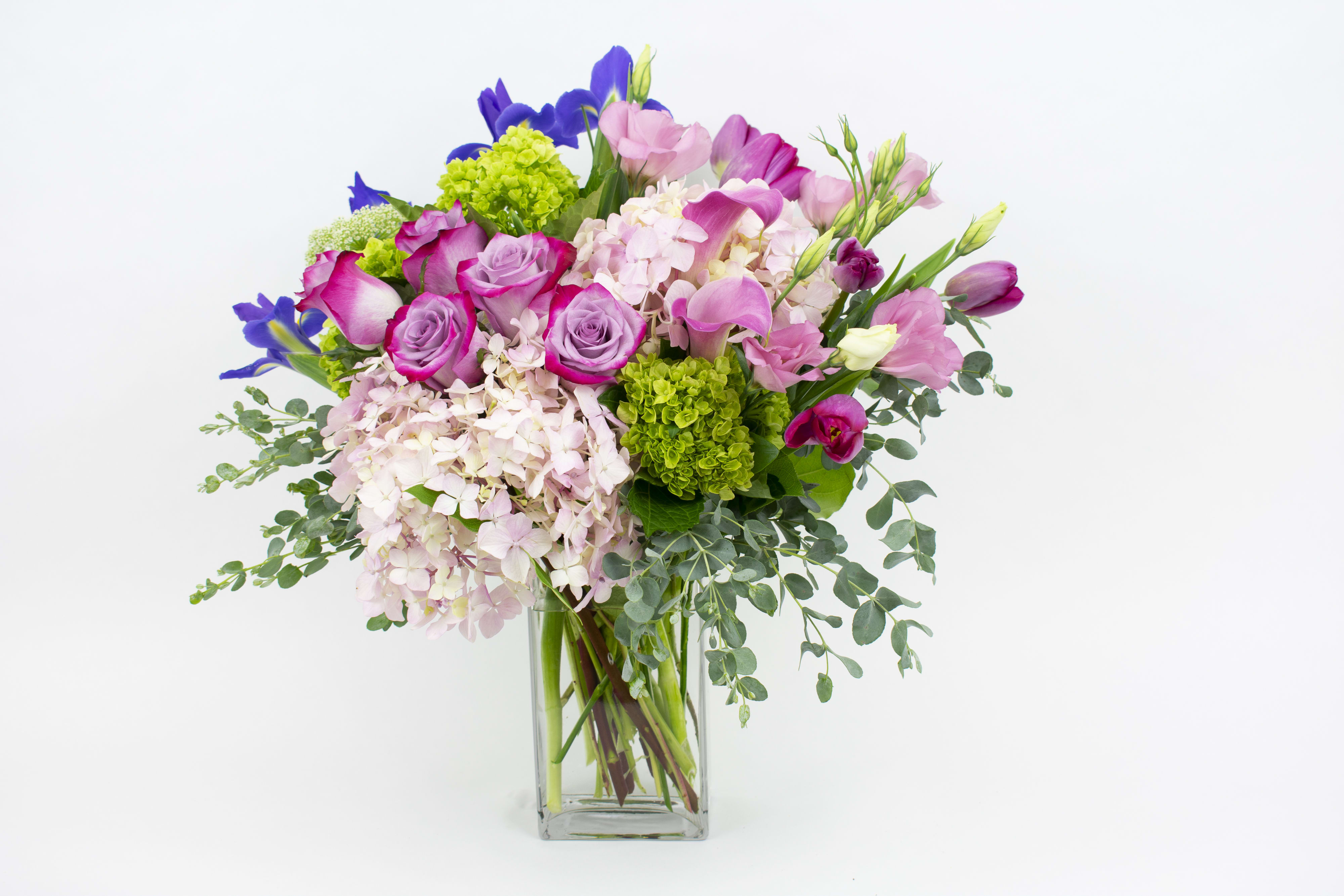 Bunch of Love - PURPLE AND PINK FLOWERS IN A VASE Soft, pretty and romantic. This Bunch of Love vase arrangement is designed in shades of pink and purple and stars an abundant variety of market-fresh blooms and foliages. Our florists use balls of fluffy hydrangea in pastel pink tones and vibrant green, combined with fresh pink tulips and pops of vivid blue irises for height and drama. Deep purple roses and elegant pink calla lilies add an opulent touch. While cottage-garden pink lisianthus, sprigs of Queen Anne’s Lace and silvery eucalyptus complete the look. Send these gorgeous flowers to wish a friend or partner a special happy birthday. Or celebrate the birth of a baby with a big bunch of blooms for the bedside. This flower design is also perfect for a romantic anniversary or out of the blue ‘I love you’ as an alternative to traditional red roses. Why not add a greeting card or quality handmade candle to match the occasion or personality?  BUNCH OF LOVE FEATURES: • Fresh pink tulips • Light pink hydrangea • Green ‘broccoli’ hydrangea • Deep purple roses • Elegant pink calla lilies • Romantic pink lisianthus flowers • Bright purple-blue iris • Queen Anne’s Lace • Mini eucalyptus foliage • Rectangular glass vase  SIZE: The STANDARD flower arrangement is approximately 15&quot; height and 15&quot; width.  ALLERGY ADVICE: This design is low in pollen and does not have a strong fragrance.  FAQ Q: What time will my flowers arrive and what if no-one is there to accept them? A: Excellent question! We’re unable to provide or guarantee specific delivery times. All our flowers are delivered anytime between 9-5pm, with exception to Sympathy designs for a funeral service. For full details around our delivery process and timings, please see our Terms and Conditions. Q: What days do you deliver flowers? A: All our flowers are available for San Francisco and Daly City delivery seven days a week, between 9am-5pm. Q: May I order for the same day delivery? A: Yes, same day deliveries are available if you place an order before 1pm. Q: May I request to change the design a bit? A; Yes, please make a note in the SPECIAL INSTRUCTION box when you place your online order. We will do our best to follow them. Q: Will my flowers look exactly as what is pictured? A: Depending on the season, colors or shades may vary. Sometimes we need to substitute flowers due to seasonal availability, but they’re always substituted for the same or greater value.  Ready to bring floral beauty into someone’s world with our gorgeous Bunch of Love? Order this gift online now or give us a call on (415) 752-2060 if you have a question or special request.