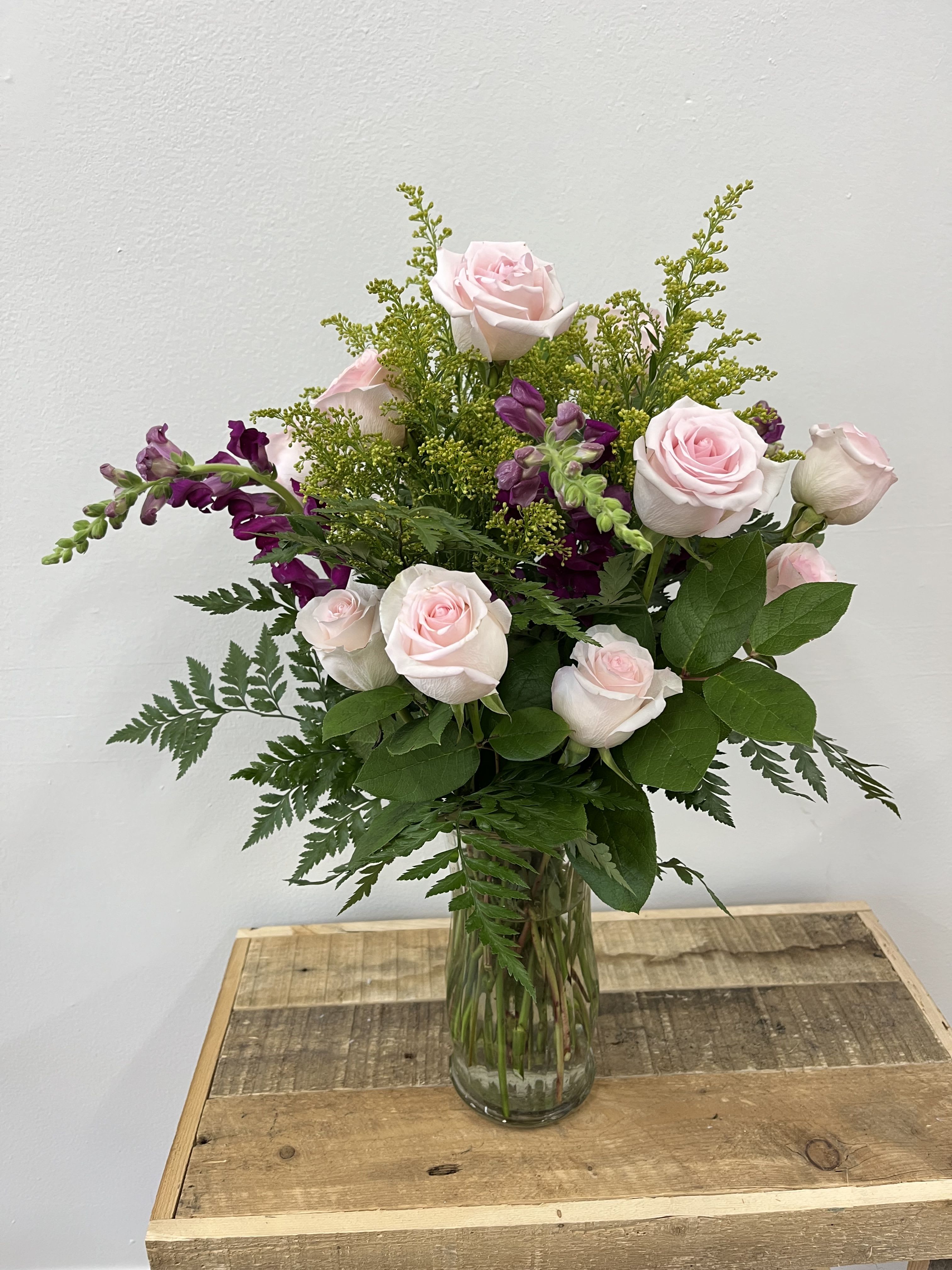 Serenity Blossom - Serenity Blossom is an elegant tall vase showcases a dozen soft light pink roses paired with vibrant purple stocks, all nestled among lush greenery. The harmonious blend of colors and textures creates a serene and sophisticated display, perfect for any occasion.