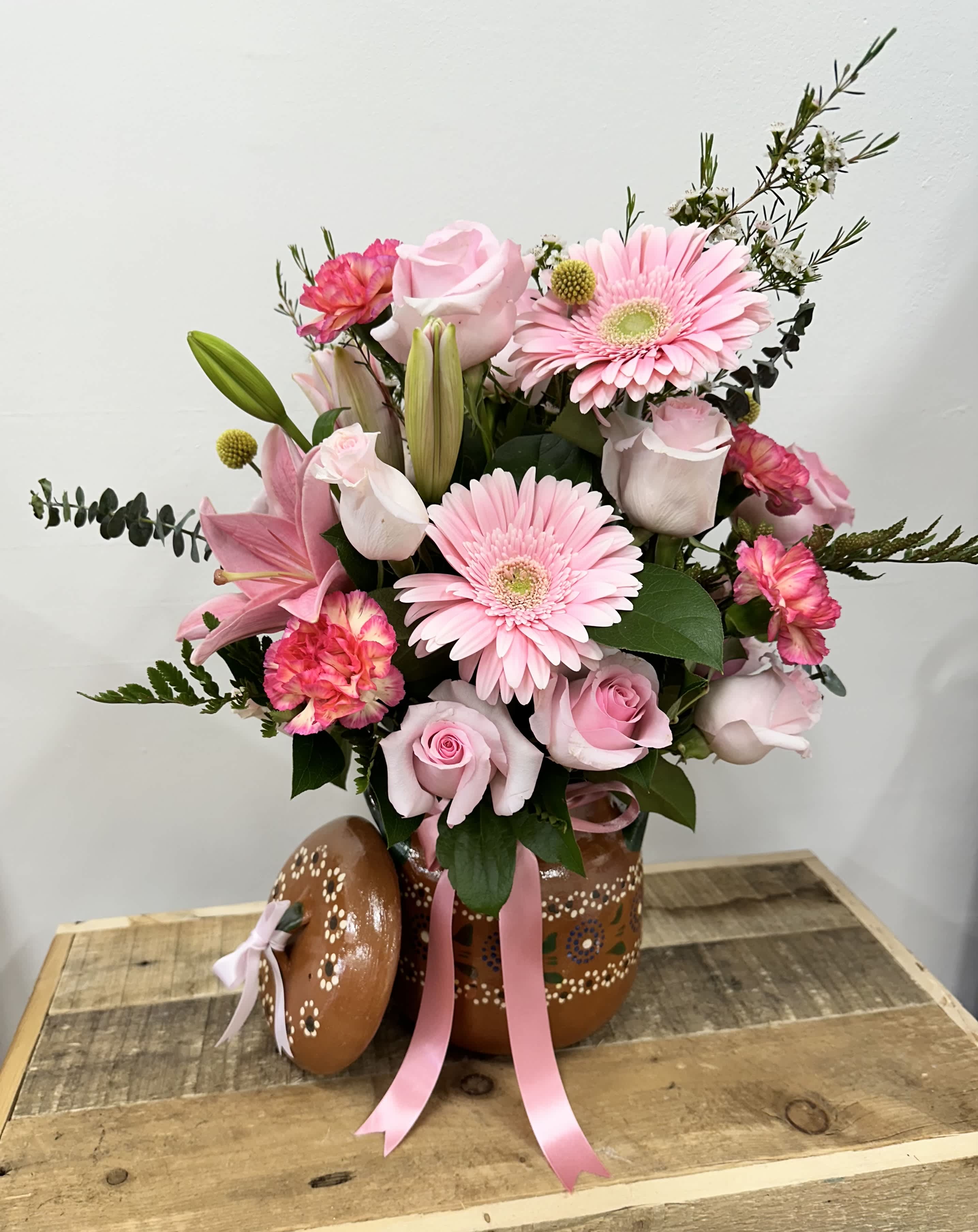 Pink Harmony Olla - A charming clay pot filled with light, pink roses, cheerful pink daisies, elegant lilies in vibrant Gerbera. This delightful arrangement offers a beautiful blend of textures and Hughes.