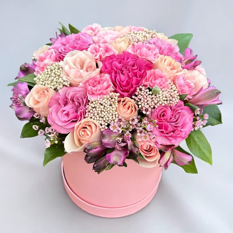 Tender Whispers #54 - Immerse yourself in the soft elegance of &quot;Tender Whispers,&quot; a delicate arrangement featuring hot pink garden roses and light pink premium roses, beautifully presented in a refined hat box. The vibrant hot pink garden roses radiate passionate love, while the light pink premium roses add a touch of timeless grace and gentle affection. This harmonious blend of colors and textures creates a captivating display, symbolizing both the depth and tenderness of true love. Encased in a stylish hat box, this arrangement is designed to enchant and serve as a cherished keepsake. &quot;Tender Whispers&quot; is the perfect choice for expressing heartfelt emotions, making it an ideal gift for anniversaries, special moments, or simply to convey your love in a gentle and romantic way.