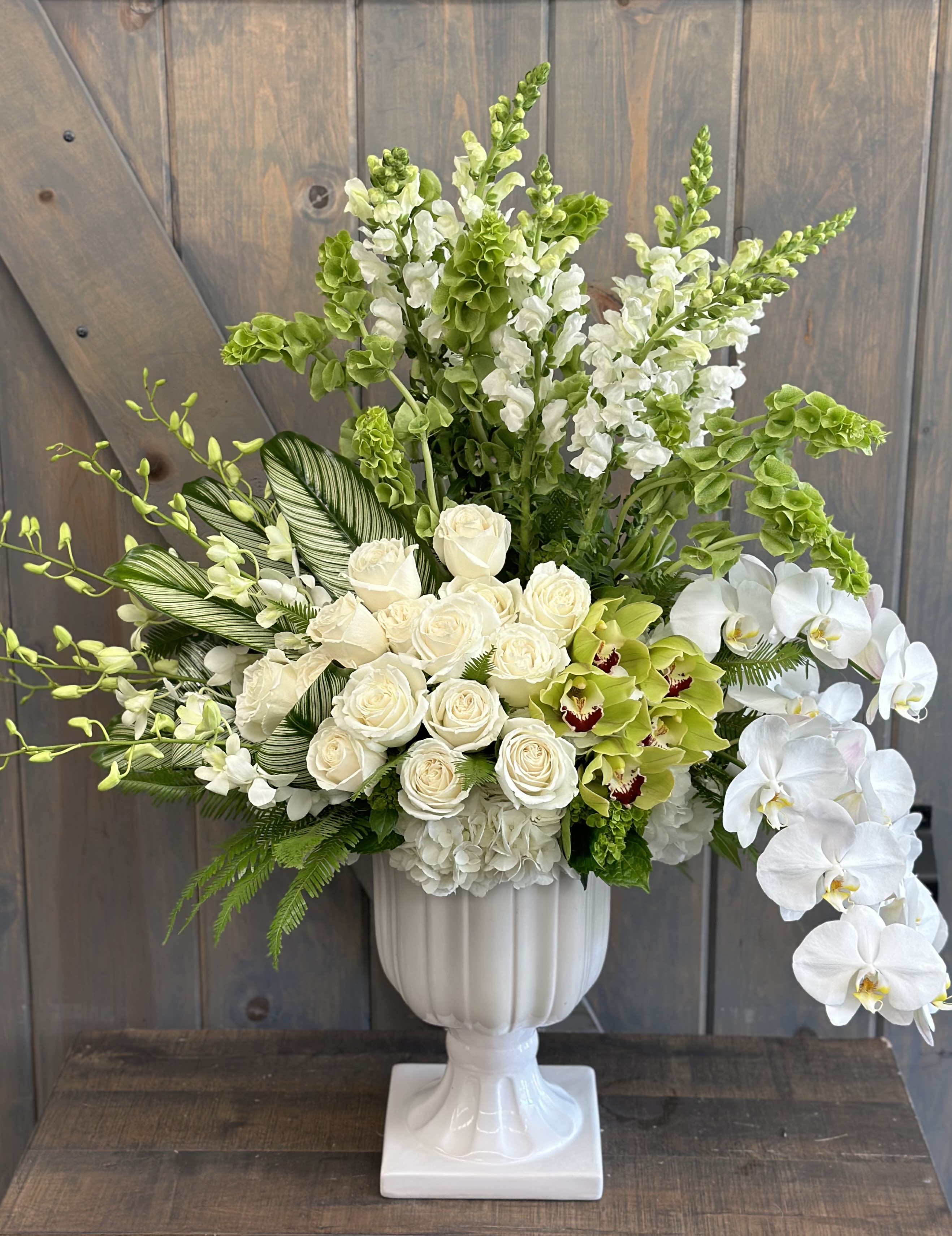 Avant-garde - A true show stopper. This design is a contemporary marvel, in all white and greens. Florals included are Roses, Hydrangea, Bells of Ireland, Snap Dragons, Cymbidiums, Dendrobiums, and Phalaenopsis, and tropical foliage.