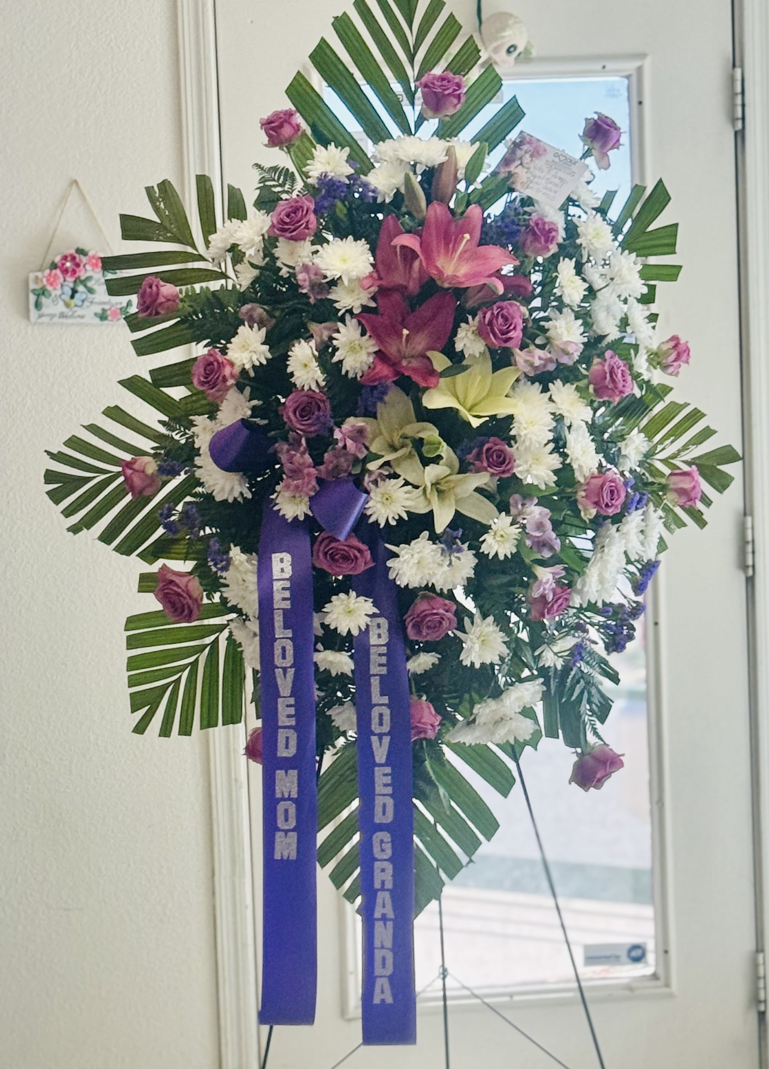 Lavender Standing Spray Lavender Standing Spray - A beautiful array of lavender and white florals arranged in a 60” easel. Accented by a purple satin bow. Name on ribbon is charged extra and is 11.99