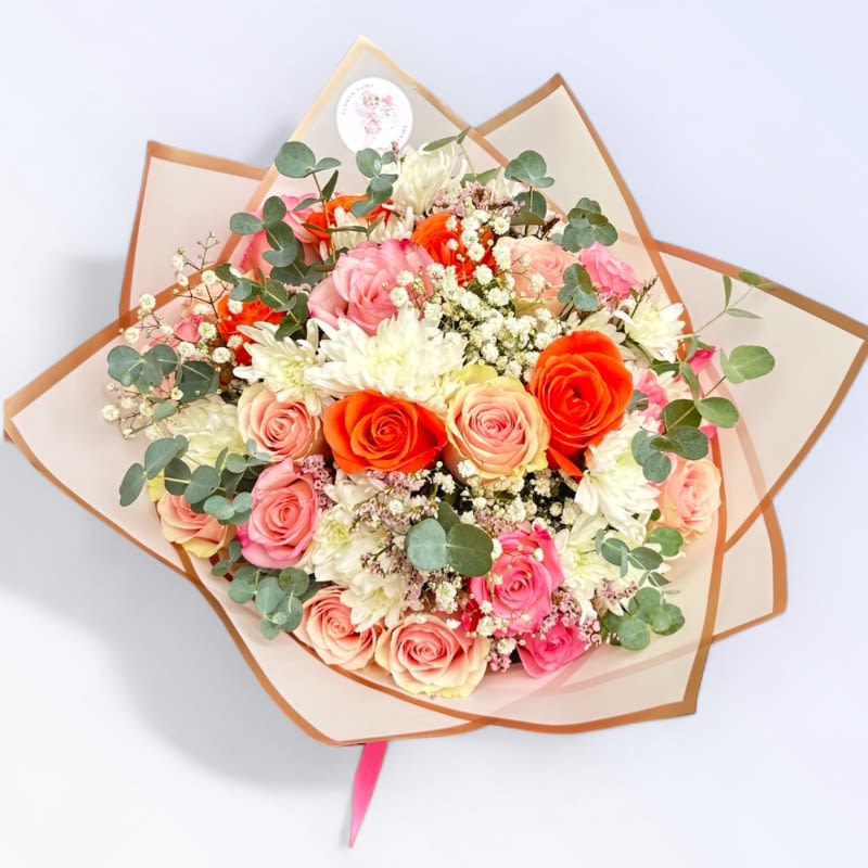 Coral Bliss Bouquet #77 - The Coral Bliss Bouquet is a charming round-shaped floral arrangement, beautifully wrapped in delicate pink paper. This delightful bouquet features a harmonious mix of coral and pink roses, complemented by pristine white mums, soft pink mini carnations, and sprigs of gypsophila. The combination of vibrant and pastel hues creates a visually captivating and elegant display, perfect for any occasion. Whether celebrating a special event or simply brightening someone's day, this bouquet exudes warmth and grace, making it a thoughtful and exquisite gift.