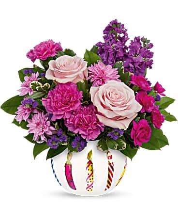Teleflora's Birthday Greetings Bouquet Teleflora's Birthday Greetings Bouquet - Light up their birthday with this unforgettable gift of perfect pink blooms in a frosted glass bowl with hand-painted birthday candles! Pink roses, purple stock, dark pink carnations, lavender cushion spray chrysanthemums, miniature lavender carnations and purple sinuata statice are arranged with variegated pittosporum and lemon leaf. Delivered in a Birthday Celebration bowl.