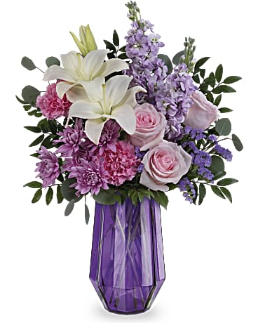 Teleflora's Lavender Whimsy Bouquet - Wow mom with this whimsical gift of pastel-hued blooms in a pretty purple glass vase with a jewel-inspired geometric design. Light pink roses, white asiatic lilies, pink carnations, lavender stock and lavender cushion spray chrysanthemums are arranged with lavender sinuata statice, silver dollar eucalyptus and huckleberry. Delivered in a Lavender Whimsy vase.