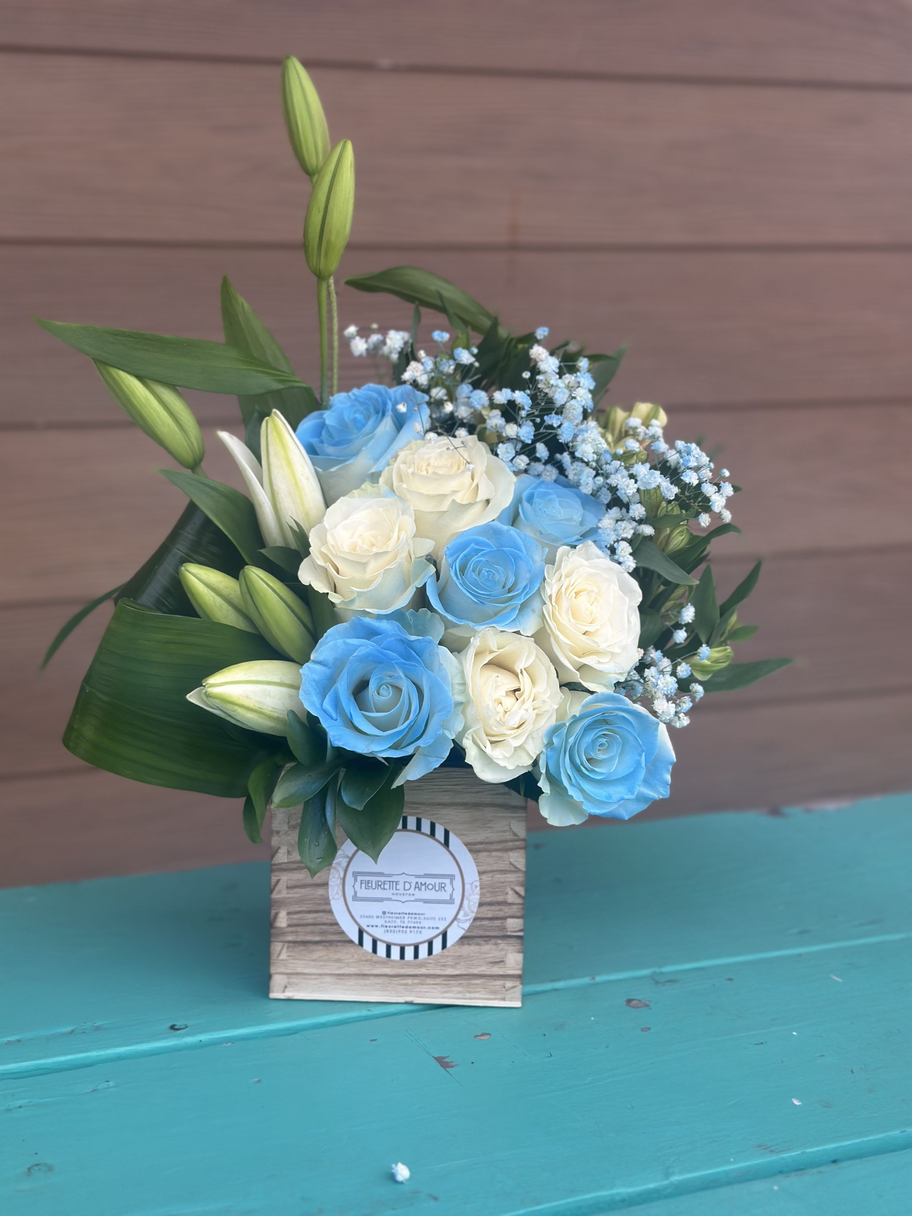 Martin New Born  - Introducing &quot;Martin New Born,&quot; a delightful small wooden box filled with lilies, alstroemerias, white roses, and light blue flowers. While the photo showcases a mix of these blooms, you can request different colors to suit your preference.  Experience the tender beauty of &quot;Martin New Born,&quot; perfect for celebrating a new arrival.  Order now to welcome a little one with this elegant and personalized floral arrangement.