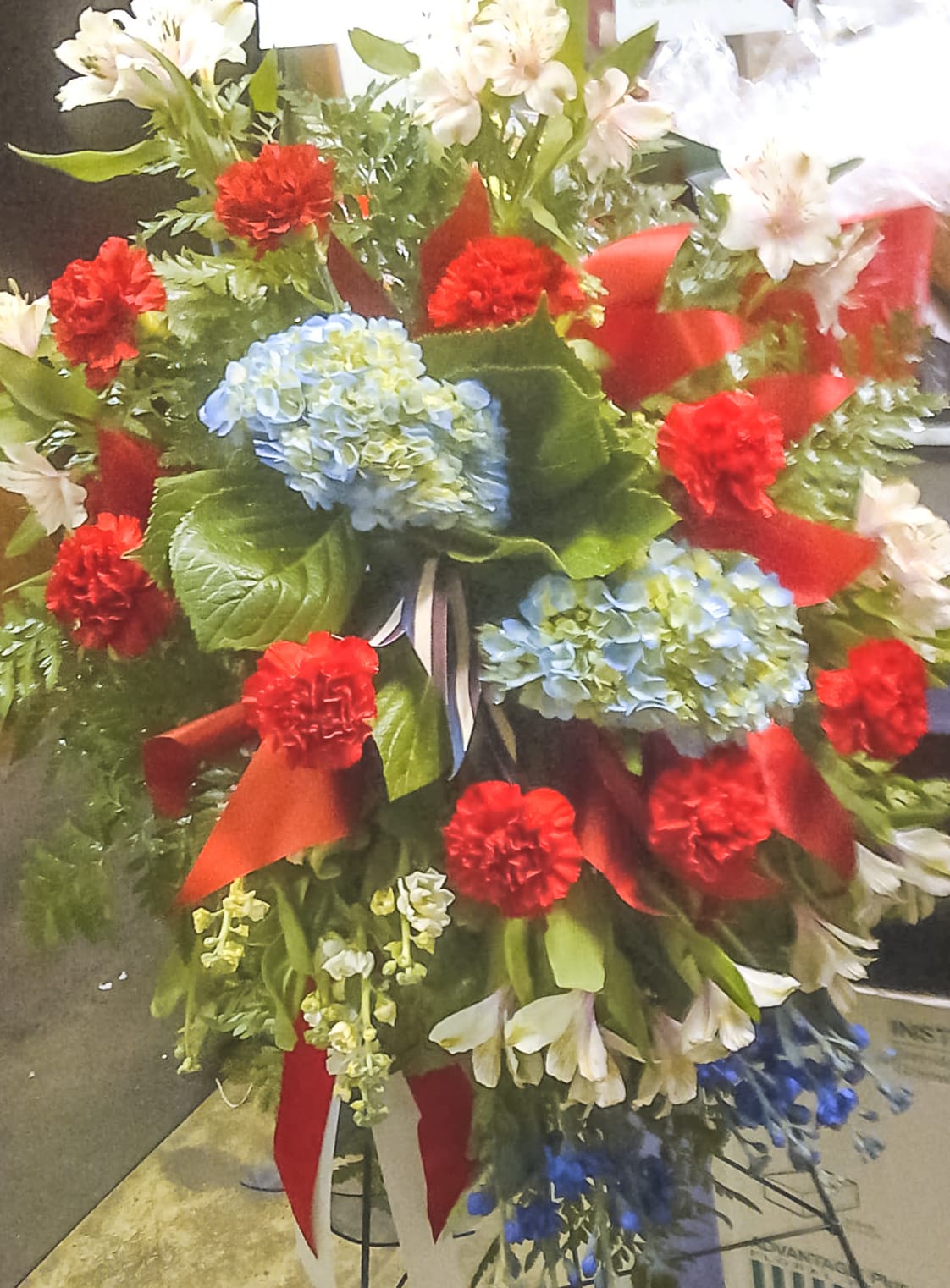 Red, White and Blue Tribute - Beautiful standing spray featuring Carnations, Alstroemeria, Delphinium, Stock and various filler with ribbon. 