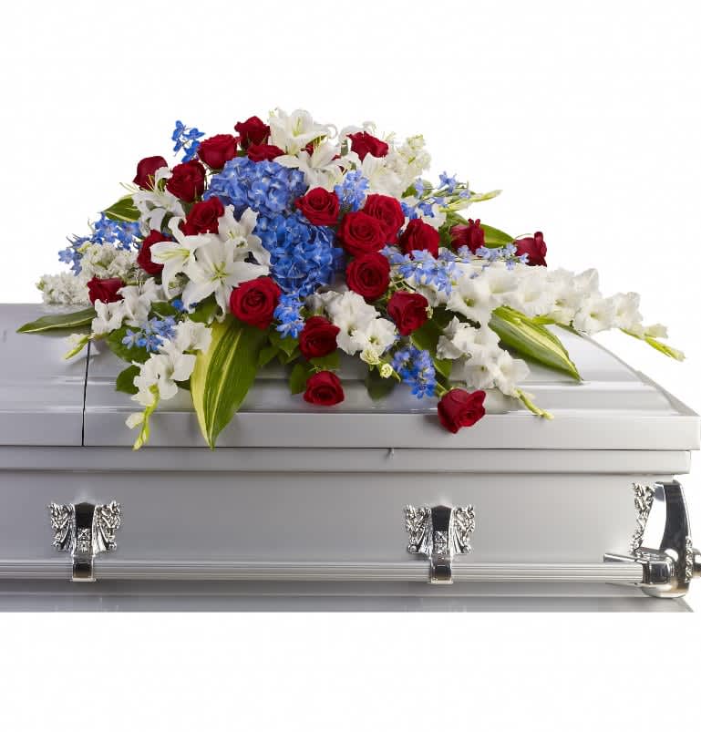 Distinguished Service Casket Spray - A beautifully patriotic way to pay tribute to a loved one. This half-couch spray sends an eloquent message of strength, respect and freedom. Brilliant flowers such as blue hydrangea, red roses, white oriental lilies and much more create this dignified way to honor the deceased. Approximately 46 1/2&quot; W x 24&quot; H